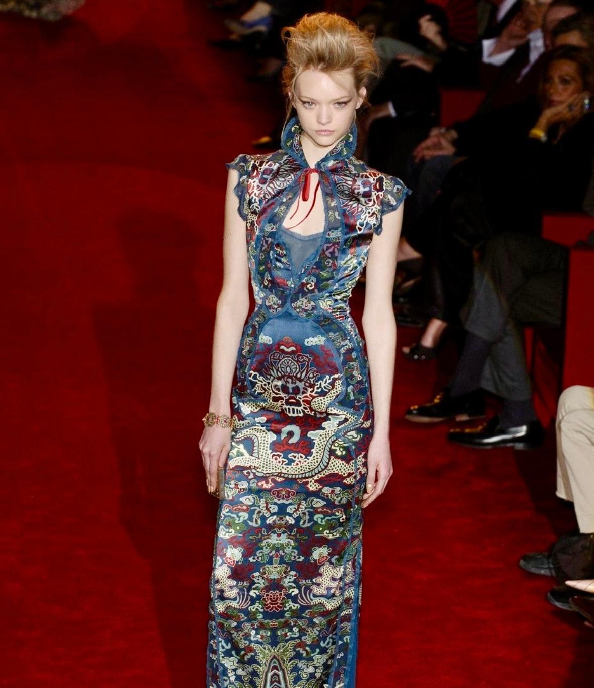 Issu de la dernière collection de Tom Ford pour Yves S.Laurent, automne/hiver 2004, ce top en soie bleue est orné d'un imprimé dragon inspiré de la chinoiserie. Dotée d'un col montant, de manches capuchon et d'une découpe spectaculaire sur le devant