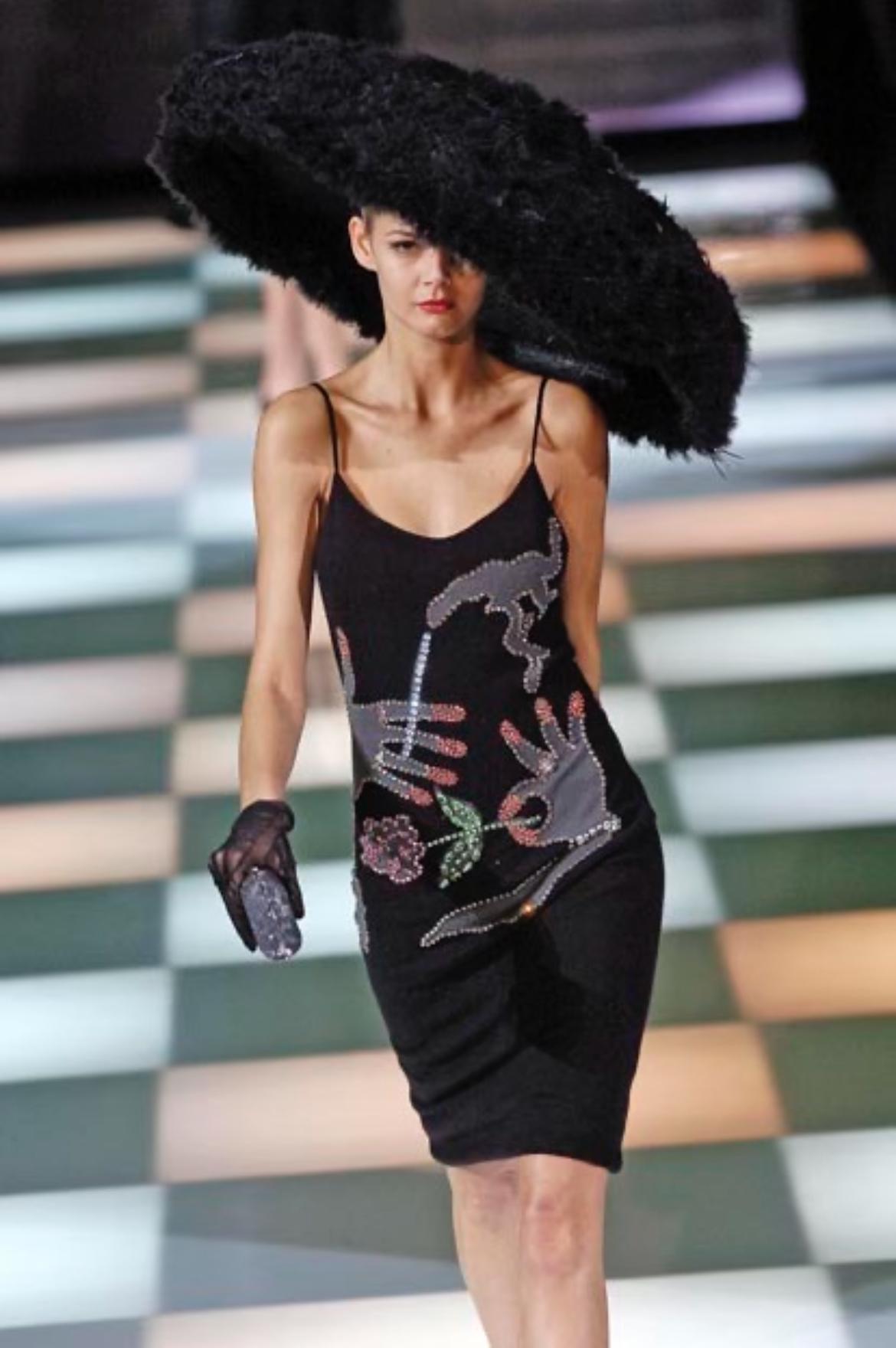 Dalla collezione Autunno/Inverno 2005 di Giorgio Armani, questo abito da cocktail in maglia nera presenta una silhouette aderente con spalline sottili e decorazioni in strass multicolore che formano mani, un fiore e un motivo di sigaretta fumante.