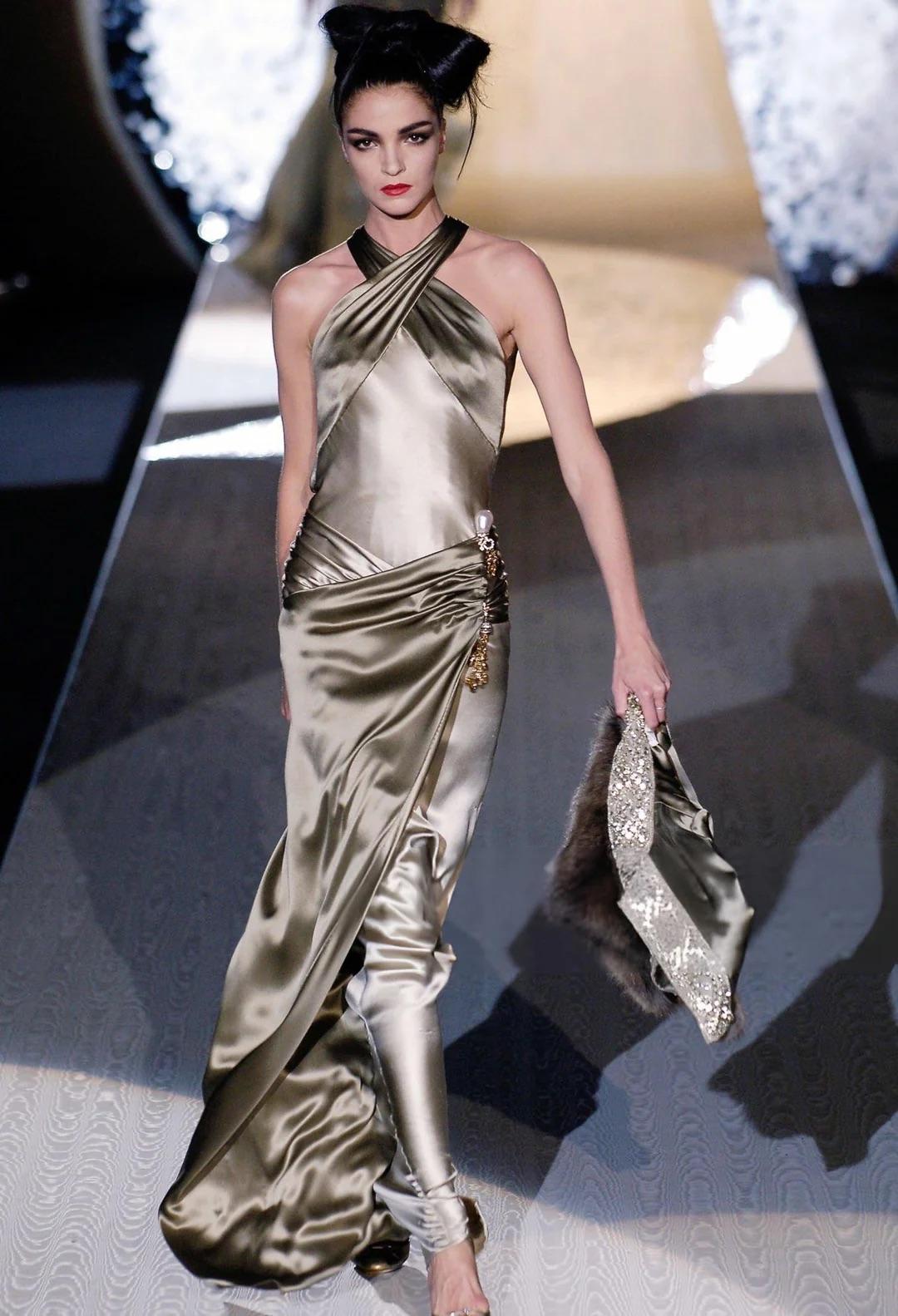 Presentamos un increíble vestido de seda verde oliva/verde salvia de Valentino Haute Couture. De la colección Otoño/Invierno 2005, este lustroso vestido de satén debutó en la pasarela de la temporada con el look 26, modelado por Mariacarla Boscono.