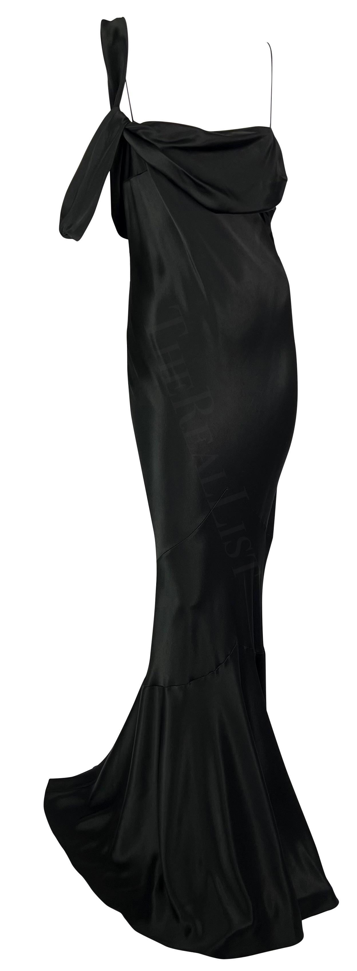 Presenting a stunning black satin John Galliano gown. From the Fall/Winter 2006 collection, this floor-length gown is constructed entirely of black silk satin. The dress features spaghetti straps, a draped accent on one shoulder, a semi-exposed