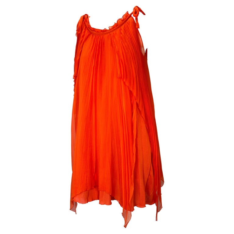 TheRealList presents: an orange pleated Christian Dior Boutique tent dress, designed by John Galliano. From the Fall/Winter 2007 collection, this beautiful dress features a wide scoop neckline with a rope-like finish that ties at the shoulders. The