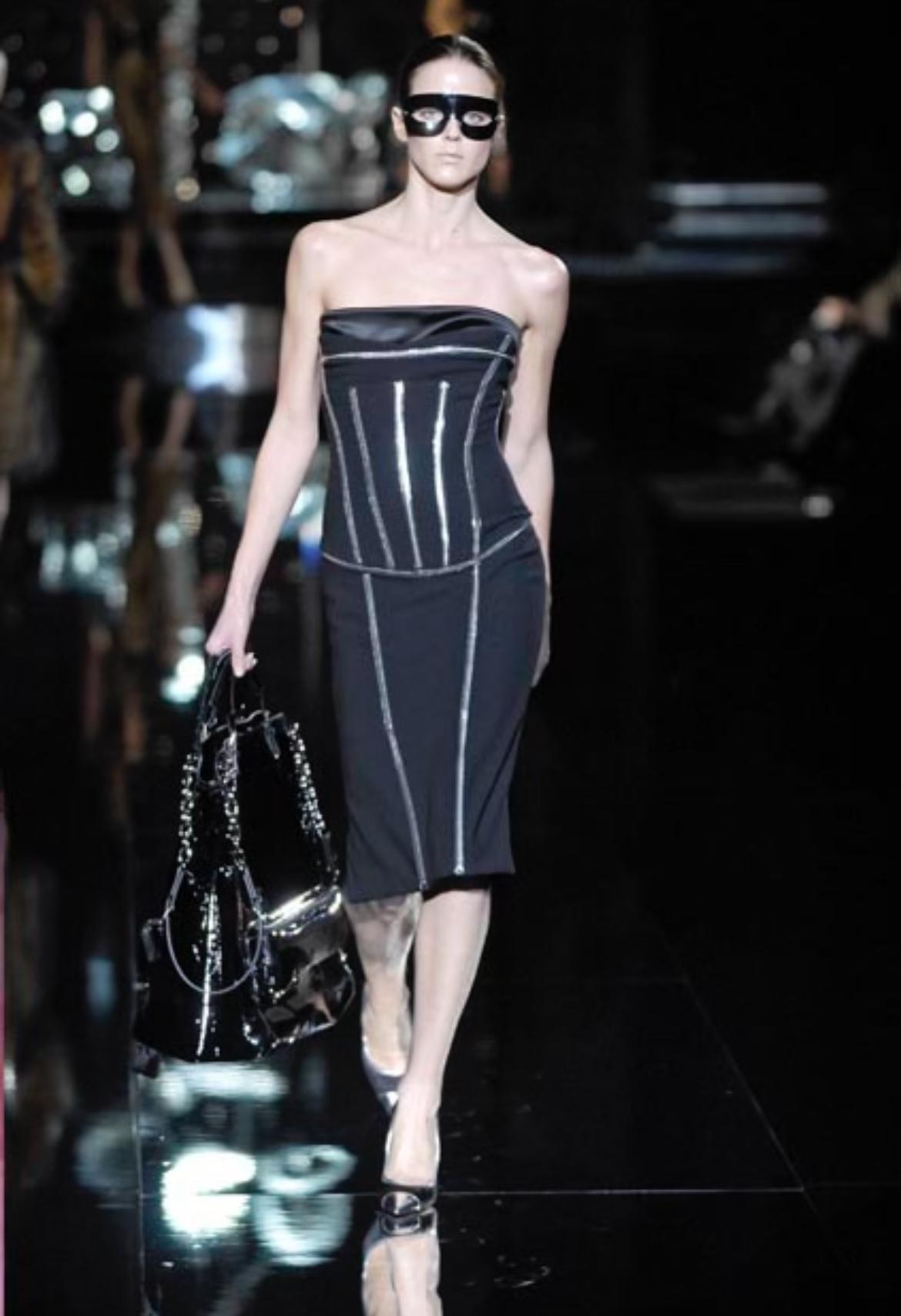 Debuting as look 13 during the Fall/Winter 2007 Dolce & Gabbana collection, this captivating black strapless dress was modeled by Shannan Click. This midi dress features exposed metal corset boning encased in transparent PVC. The distinctive boning