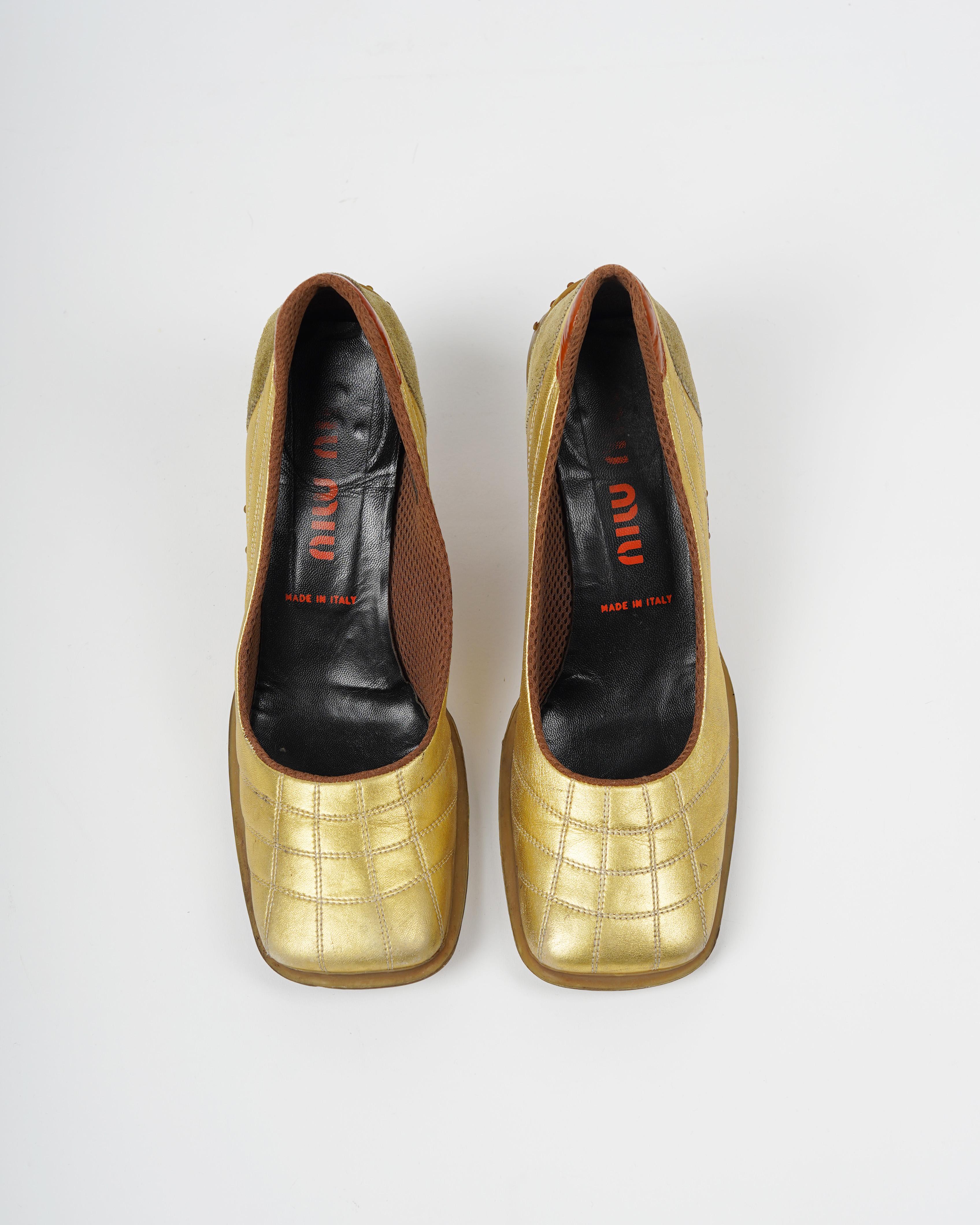 Ces talons de Miu Miu FW 1999 à semelle bulle or métallisé sont un exemple frappant du langage de conception audacieux de la marque. Fabriquées en Italie, ces chaussures présentent un mélange unique de daim, de cuir verni et de cuir métallisé doré
