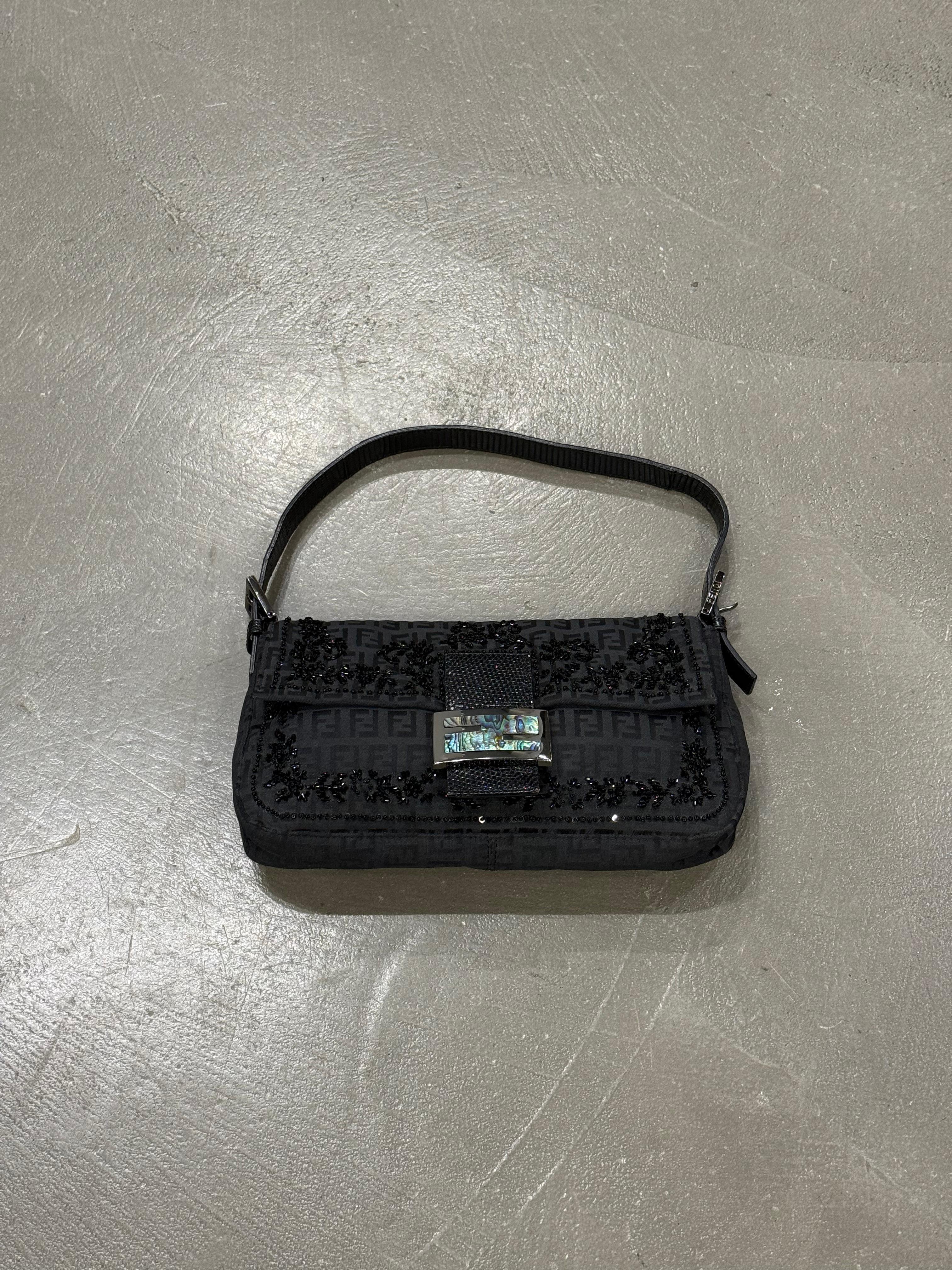 2000s Fendi Baguette Zucchino con inserti lucertola perline e fibbia madreperla.
Questa splendida borsa vintage rappresenta un pezzo iconico di alta moda, perfetto per le collezioniste e le amanti dello stile raffinato. Realizzata in tessuto nero
