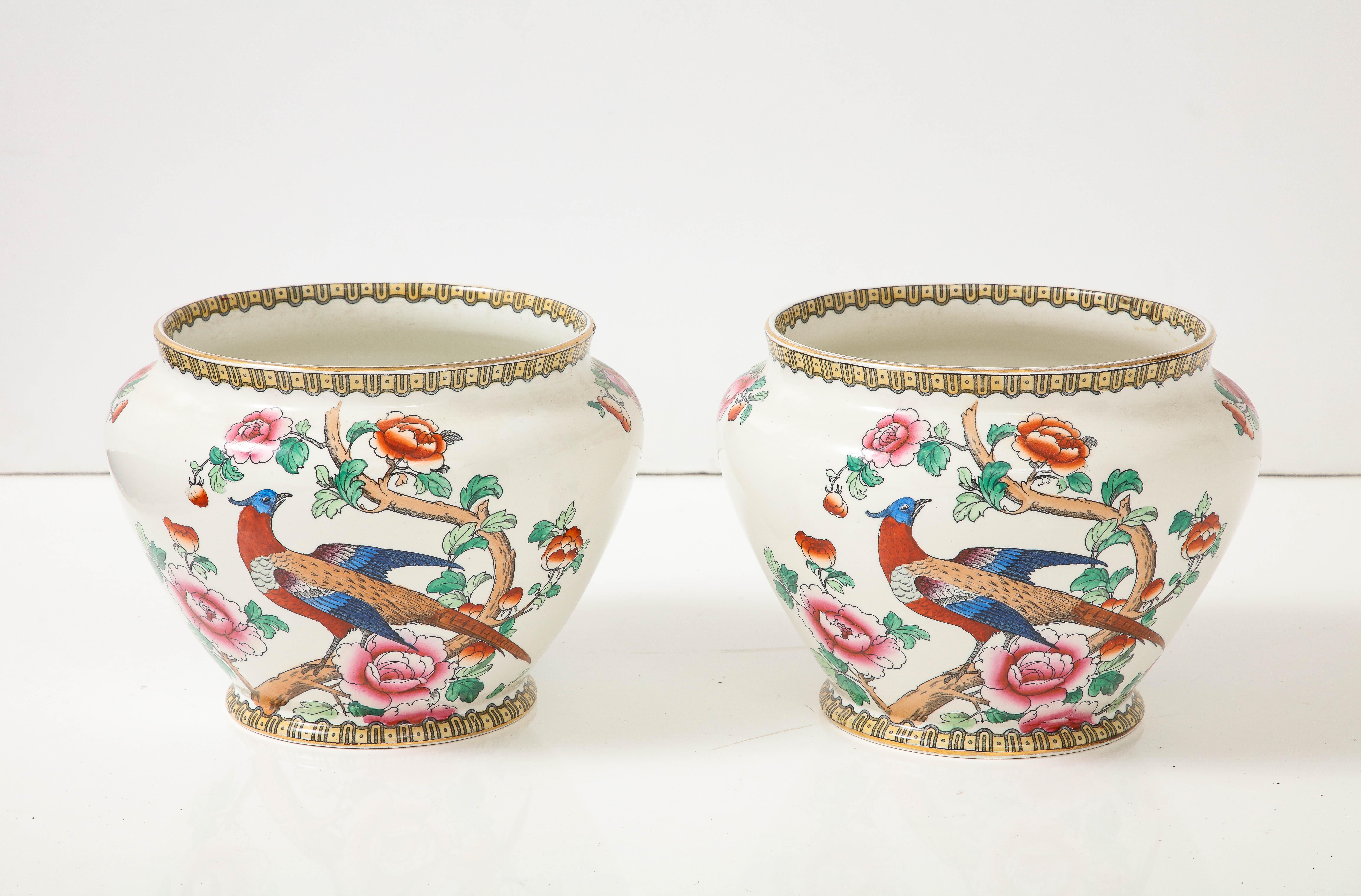 Pair of hand decorated earthenware cache pots depicting colorful pheasants and exhuberant florals. Cream earthenware background contrasted with vibrant colors. Each marked on bottom, F. Winkle and Company, England.