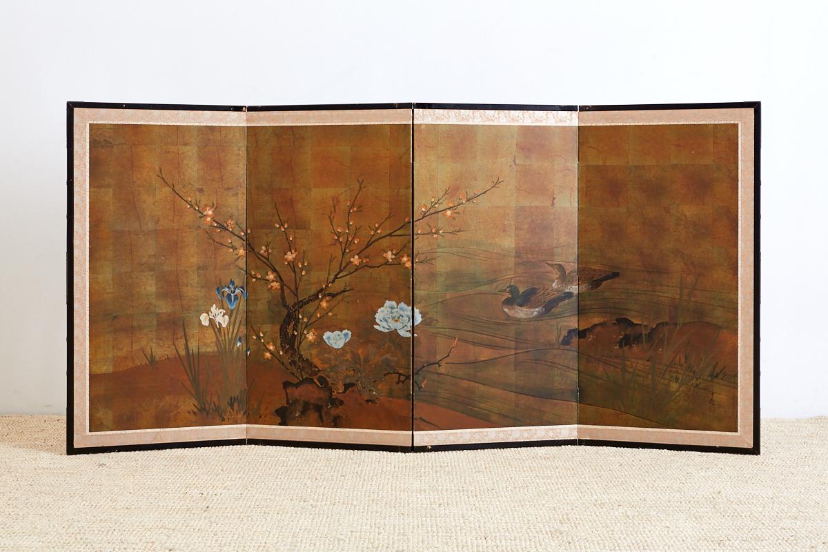 Hand-painted Japanese four-panel byobu screen of ducks at a water's edge and flower blooms. The screen is painted on a gilt square background and signed on the right side bottom. Set in an ebonized wooden frame with a silk brocade border.