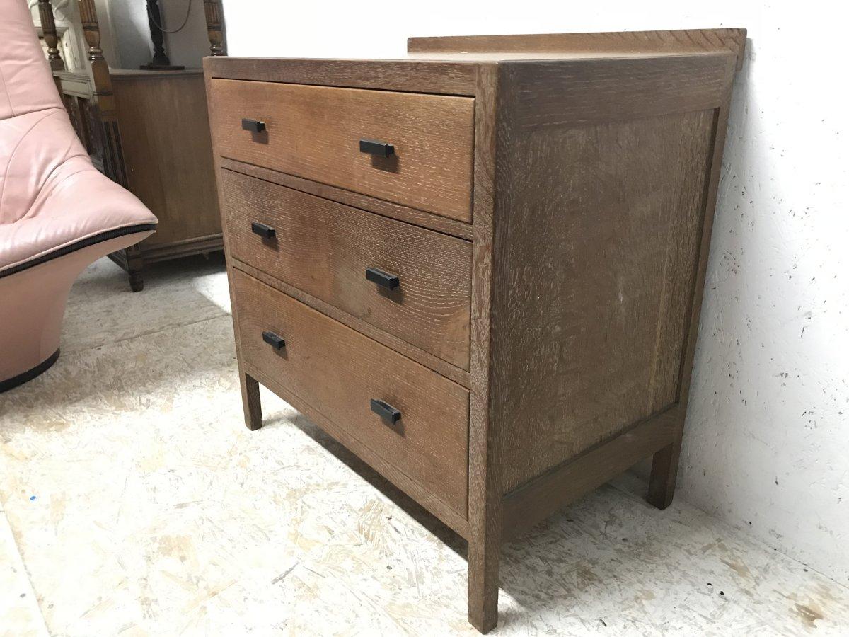 Heals attributed, a limed oak petite chest of three drawers with shaped ebonized handles.