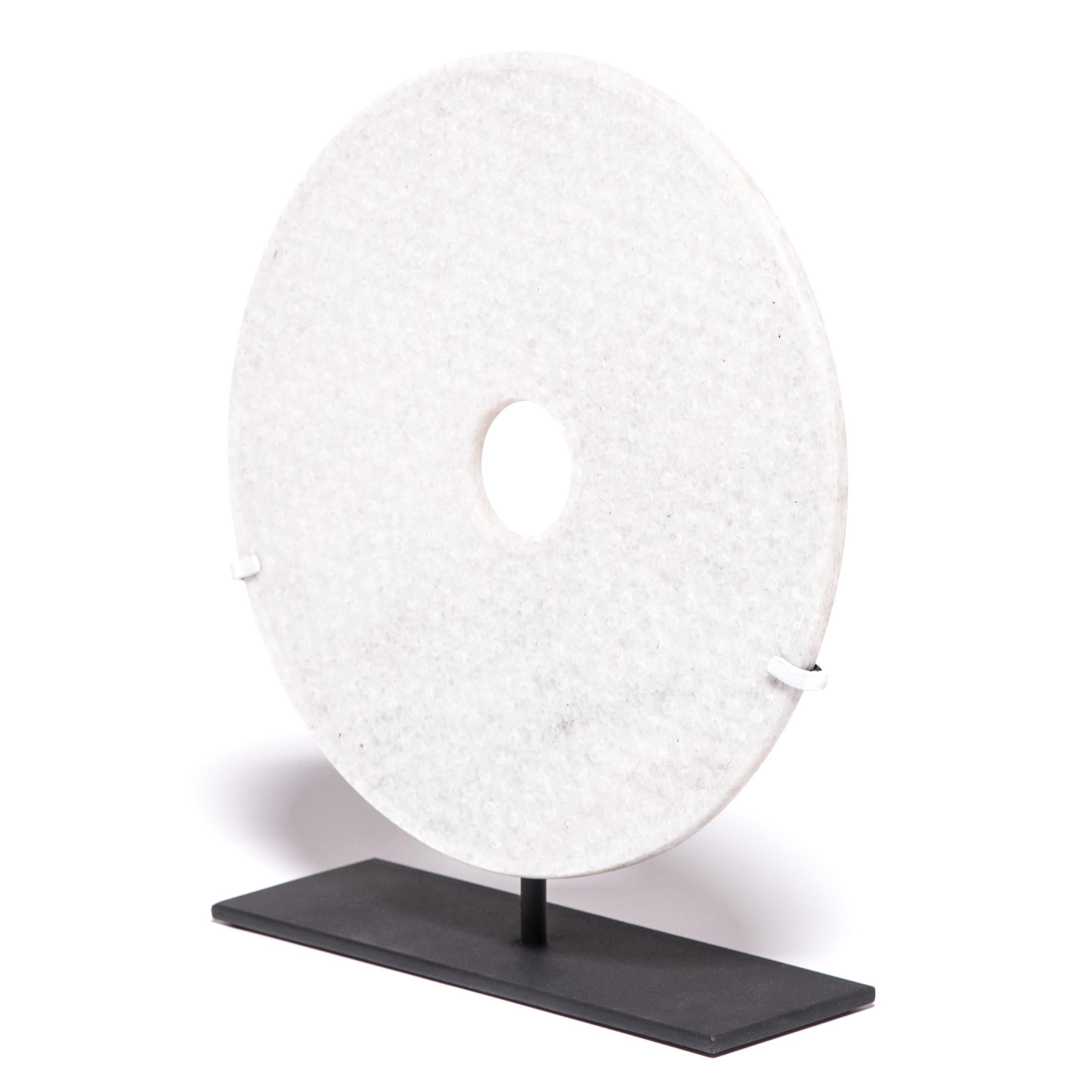 With its speckled cream color and perfectly round form, this white hardstone disc has a certain celestial quality, like a full moon gleaming in the night sky. Known as “bi,” these round discs with a circular hole in the center date all the way back