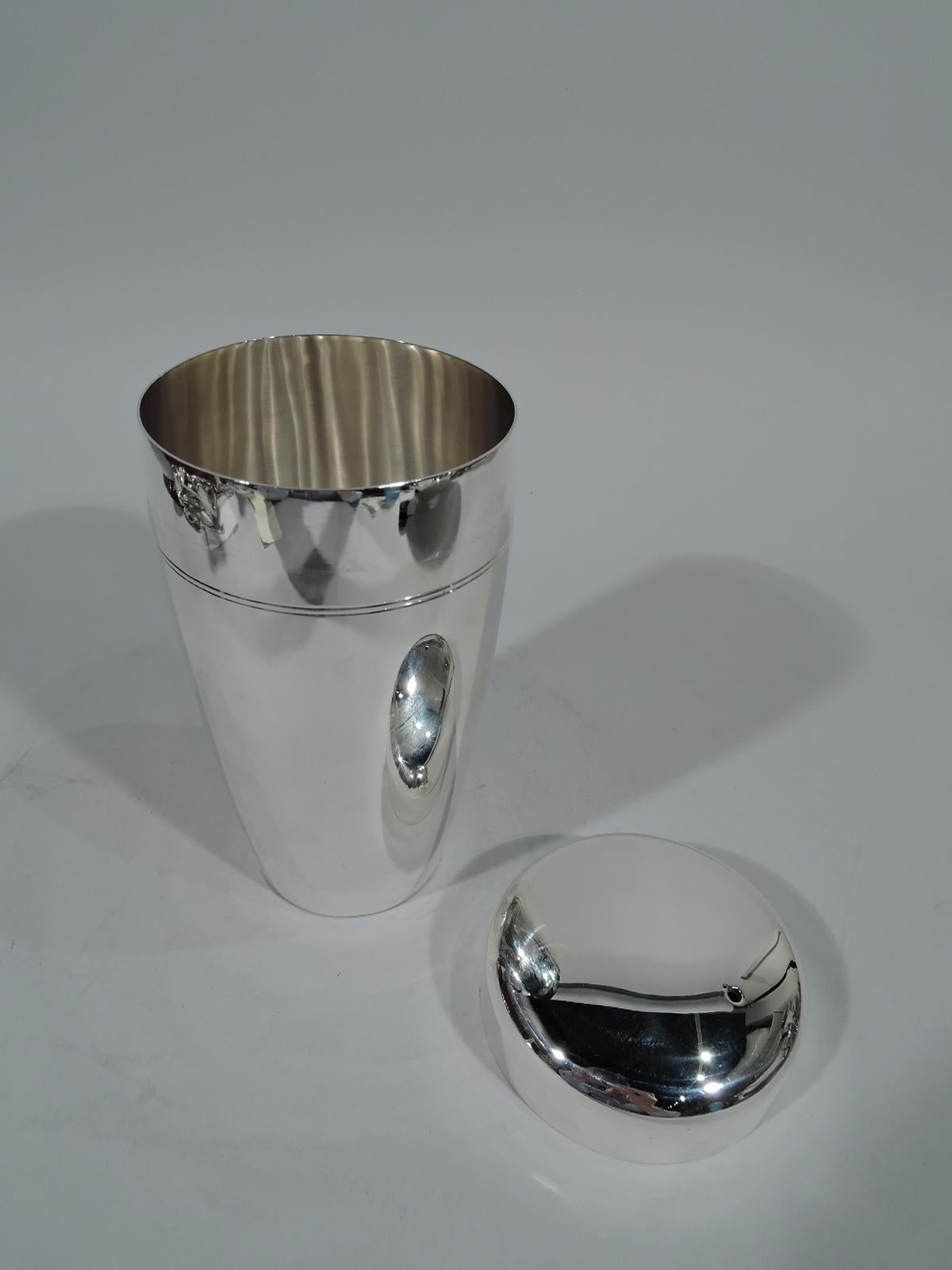 Mid-Century Modern sterling silver cocktail shaker. Made by Tiffany & Co. in New York. Curved and tapering sides with incised bands, and gently curved cover. Spare and functional – perfect for pouring over ice. Hallmark includes pattern no. 60551