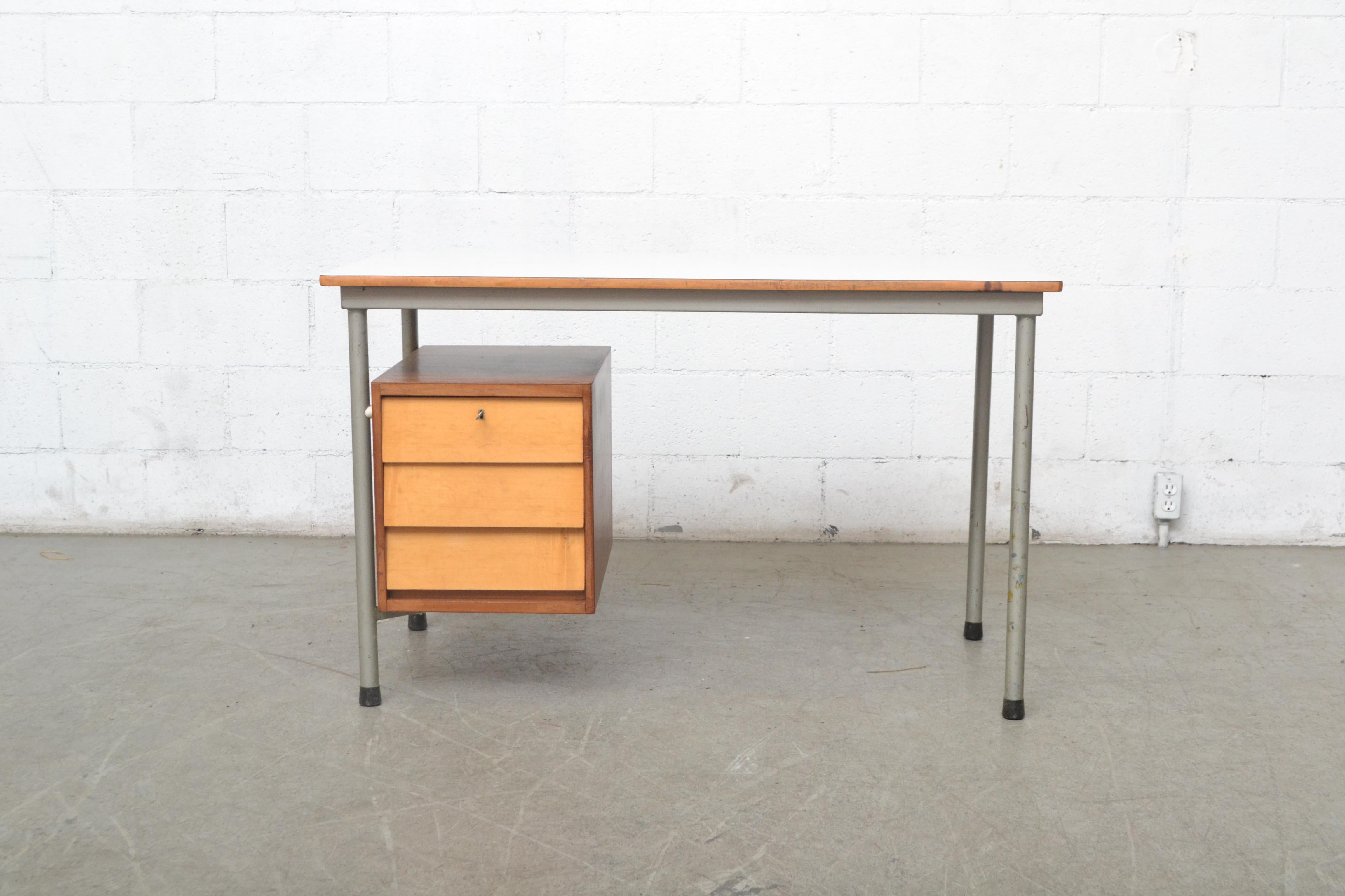Modernist Dutch industrial desk with suspended drawer cabinet. Lightly refinished two-toned wood; Teak exterior with three birch faced drawers. Original white formica top. In very original condition with visible wear and tear to the entire desk.