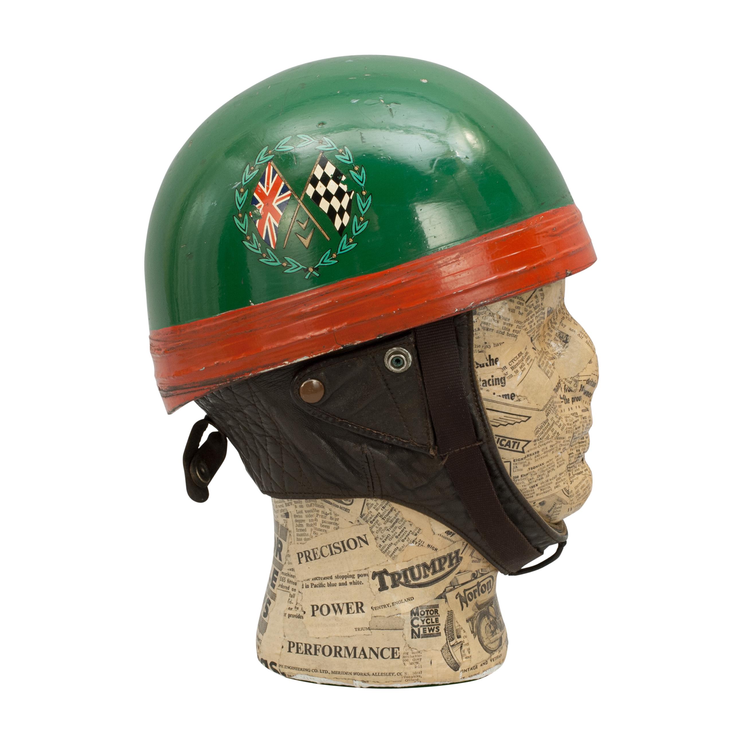 Vintage racing Cromwell crash helmet.
A green painted motorcycle, pudding basin shape helmet made in England by Cromwell. There are decals on the helmet, Castrol on one side and crossed Union flag with chequer flag surrounded with a laurel wreath