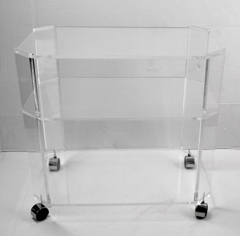 Nice clean serving or bar cart in solid Lucite. The cart has three shelves each having cut corners. Lowest shelf 3 inch H x middle shelf 17.5 H x upper shelf 25.50 H. Vintage 1970s glam item.