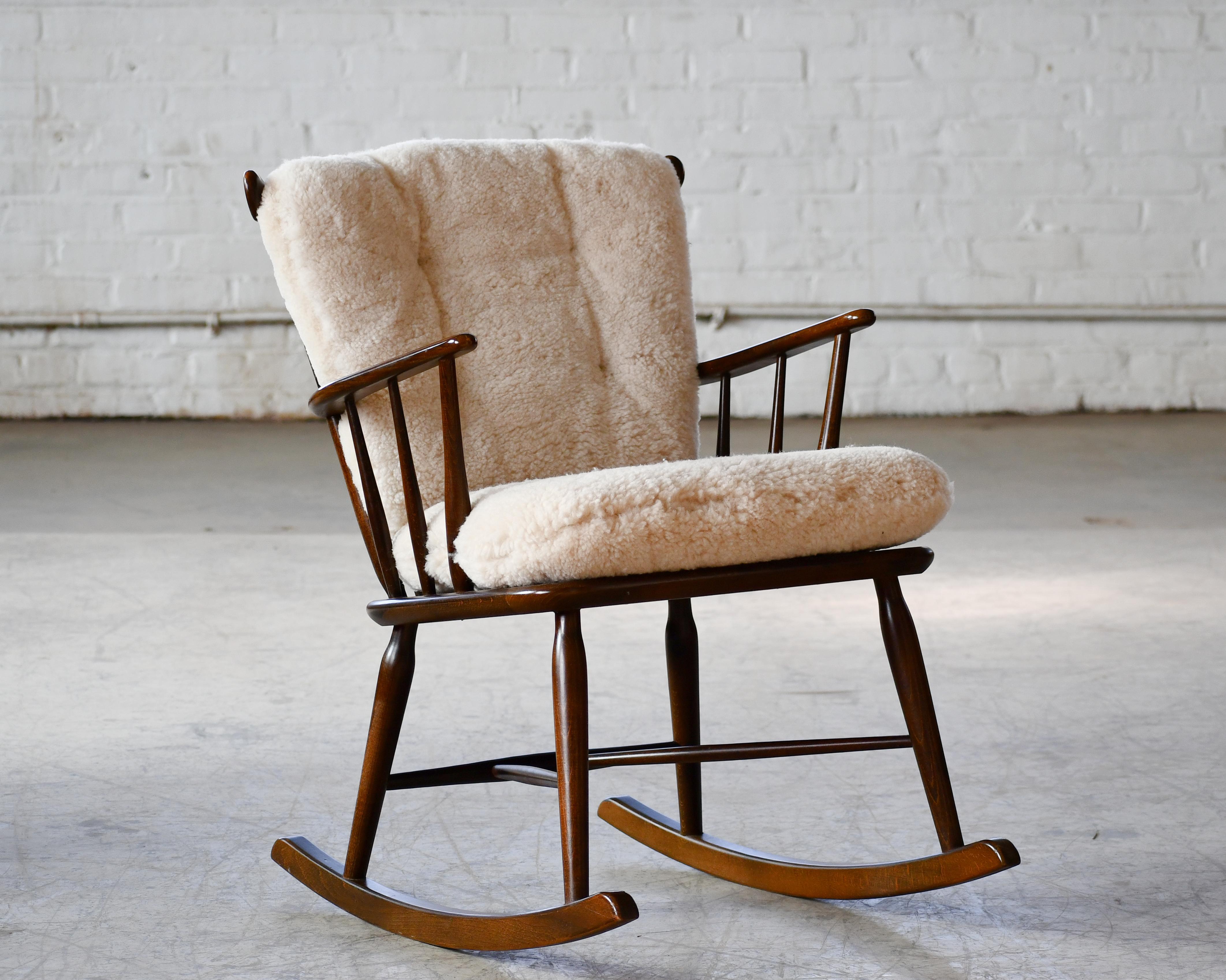 Great little low back spindle back rocking chair from Faarstrup Mobler, Denmark made circa 1950. We re-upholstered the chair with new cushions in an exuberant curly sheepskin (s520C from Garrett Leather) in a putty color and cognac colored leather