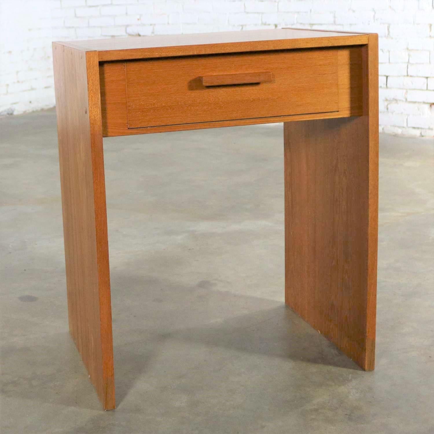 Handsome Scandinavian Modern teak single drawer nightstand or tiny desk by Faarup Mobelfabrik. It is in wonderful vintage condition. We have noticed a faded strip on the bottom two inches of the inside of each leg panel. Please see photos, circa