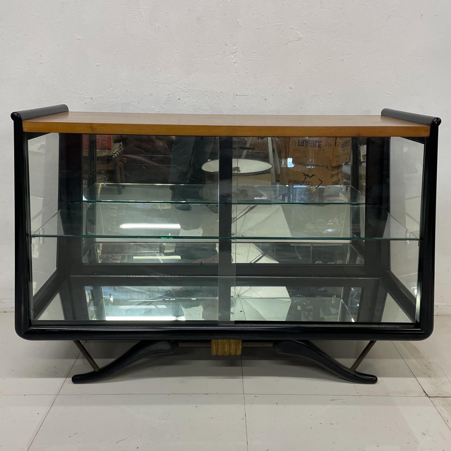 
Magnificent Modernism style of Eugenio Escudero
Mahogany Gilt Glass Vitrine Cabinet Display Showcase.
Unmarked.
Solid mahogany black lacquer finish.
Side glass and front glass sliding doors. Interior has mirrored wall.
Detailed curved sculptural