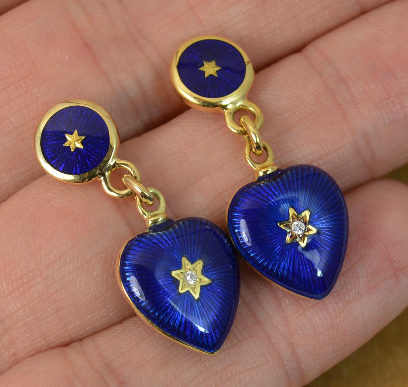 A stunning pair of Faberge designer drop dangle earrings.

Solid 18 carat yellow gold example.

Designed with a circular disc panel to top with plain gold centre and rim with Royal blue enamel in between.

Below is a puffed heart with natural