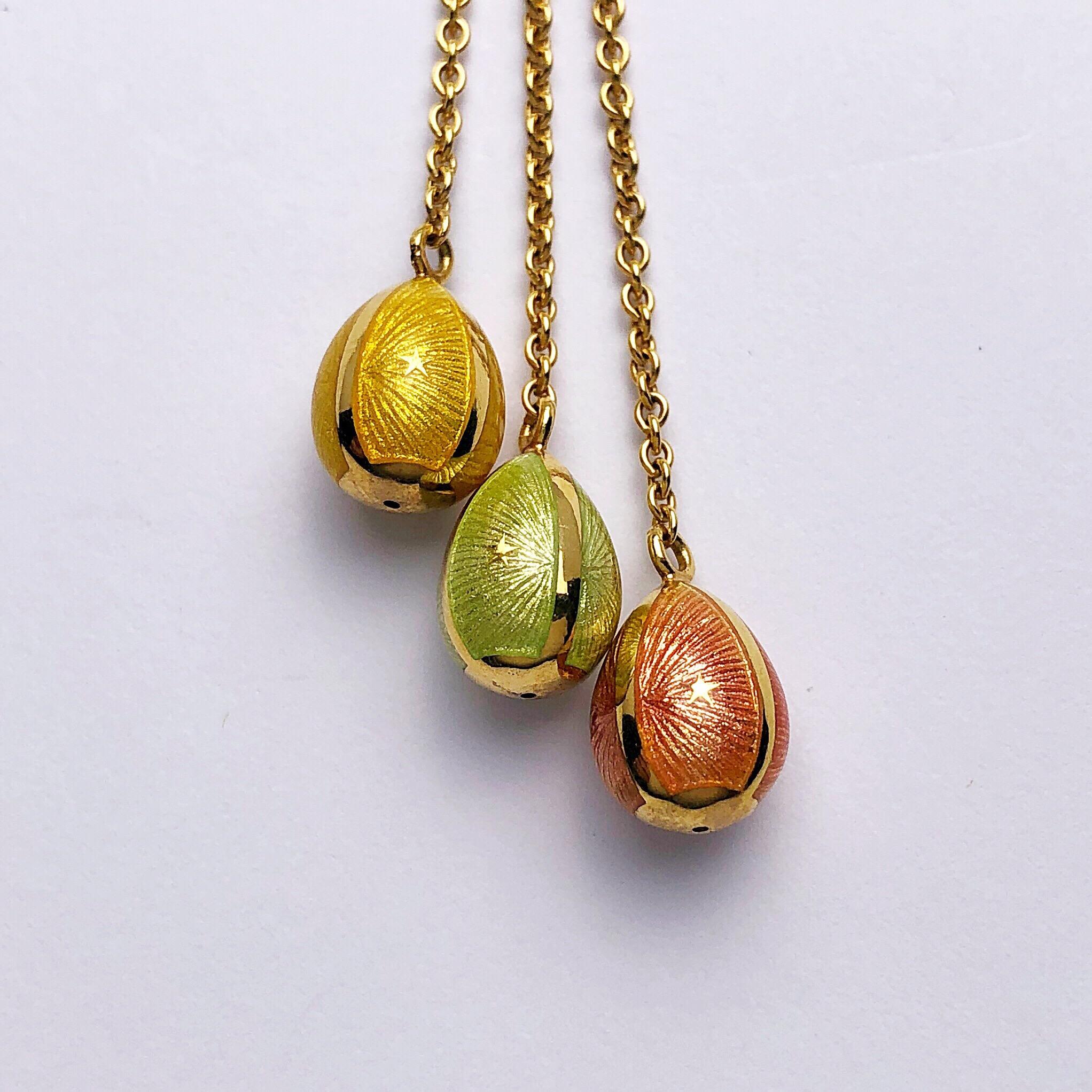This modern 18 karat yellow gold Faberge pendant by Victor Mayer features 3 hanging eggs in peach, yellow and mint guilloche enamel. The enamel eggs are hanging from an 18 karat white gold and diamond open circle. The pendants eggs were crafted in