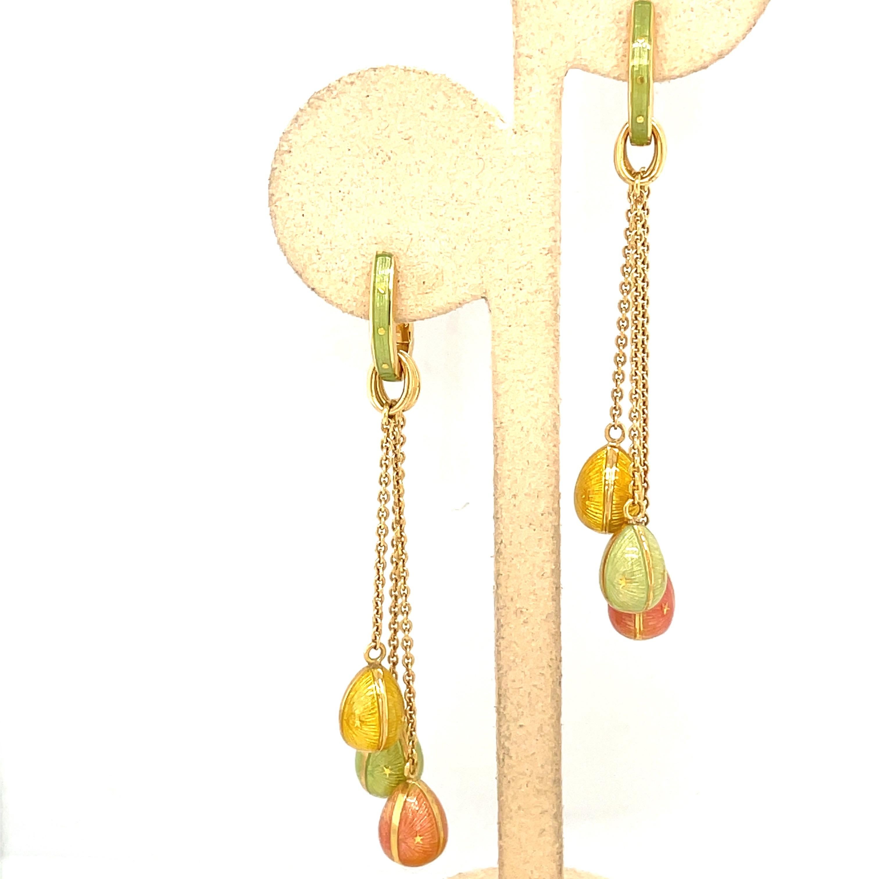 These modern 18 karat yellow gold Faberge earrings were crafted by Victor Mayer. Each earring features 3 hanging eggs in peach, yellow and mint  green guilloche enamel. The enamel eggs are hanging from an 18 karat yellow gold and mint enamel huggy