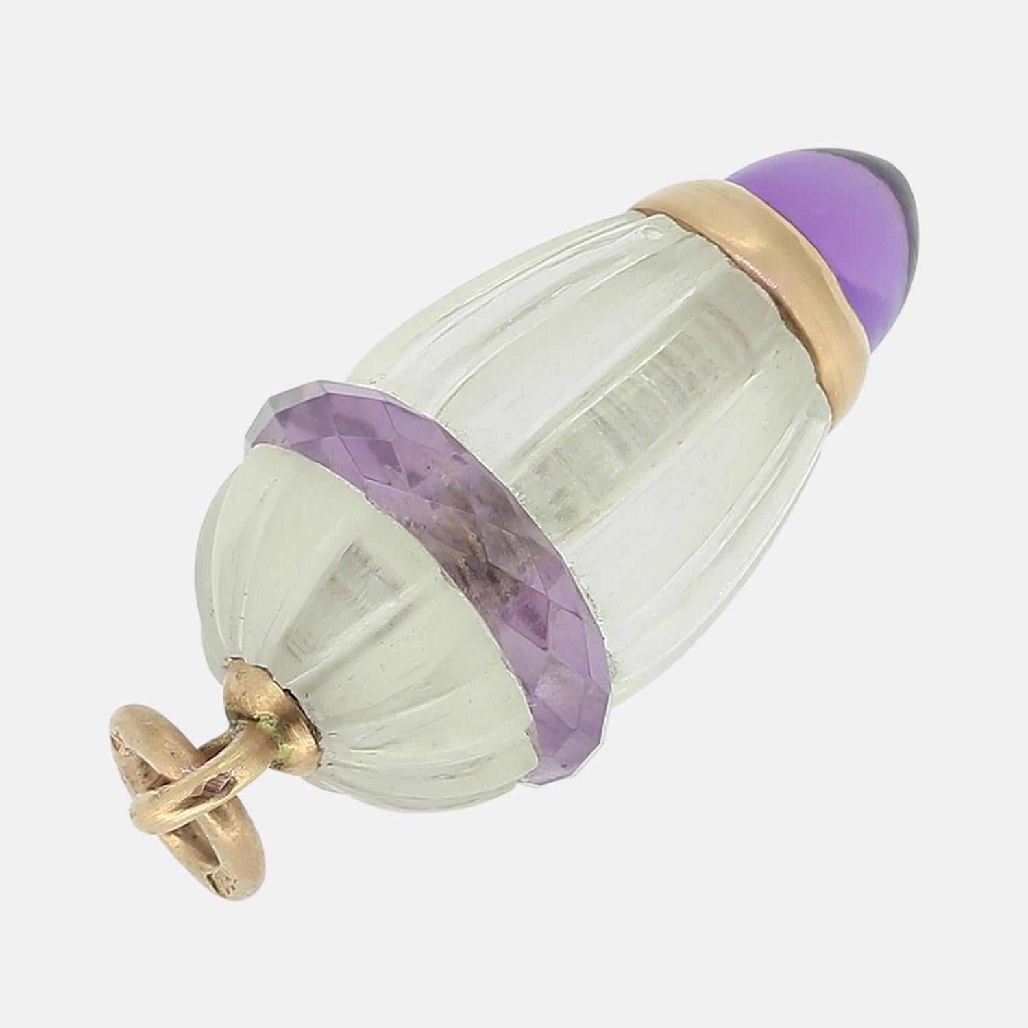 Ecco un ciondolo unico del famoso creatore di gioielli di lusso Fabergé. Il design è caratterizzato da un corpo in quarzo incolore, elegantemente intagliato con scanalature verticali. Il quarzo è circondato da una fascia sfaccettata di ametista