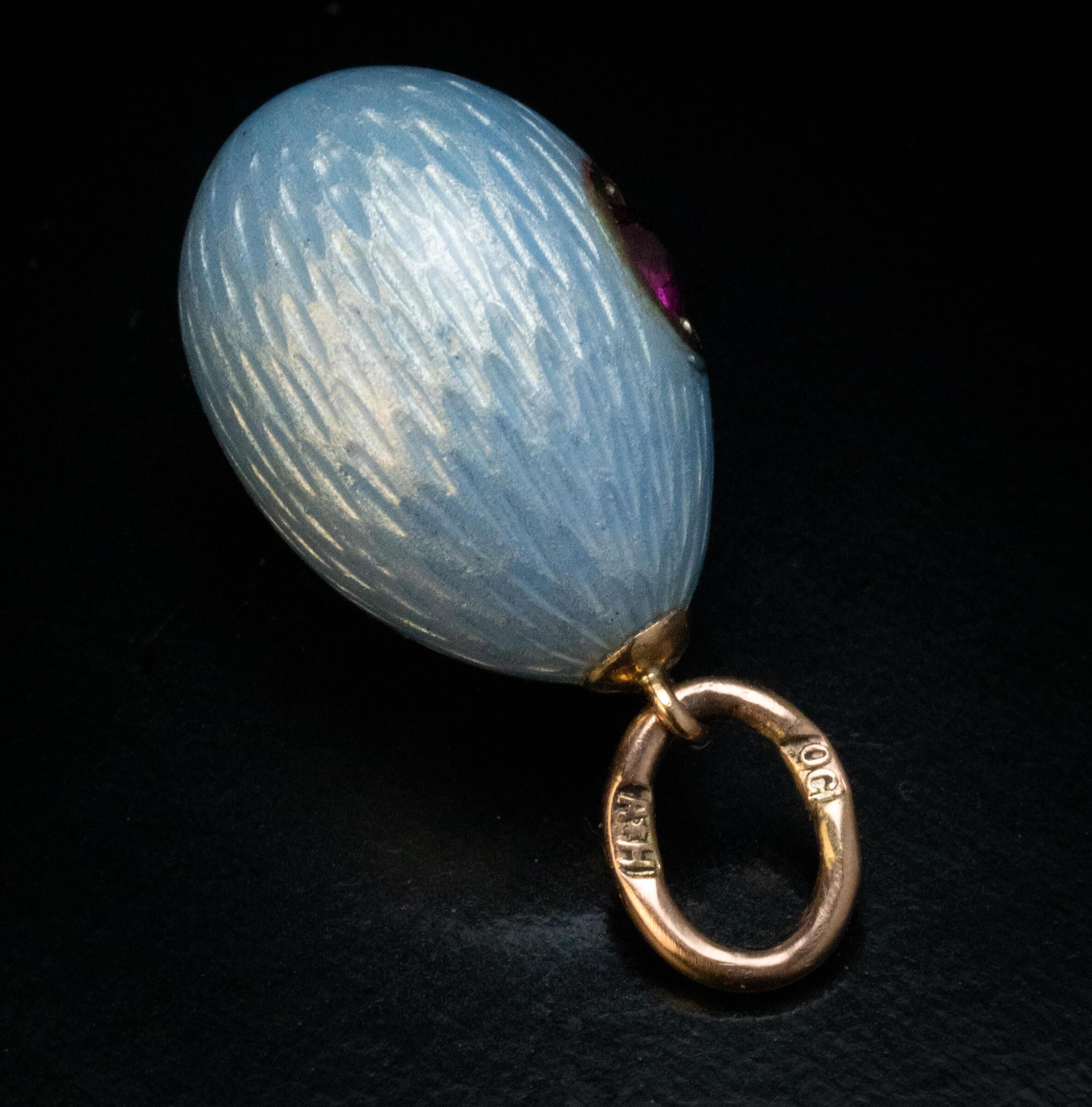 Made in Saint Petersburg between 1908 and 1917.  This FABERGE miniature egg is covered with a silver blue translucent guilloche enamel of a very fine quality. One side of the egg is embellished with a ruby.  The egg is marked with 56 zolotnik old