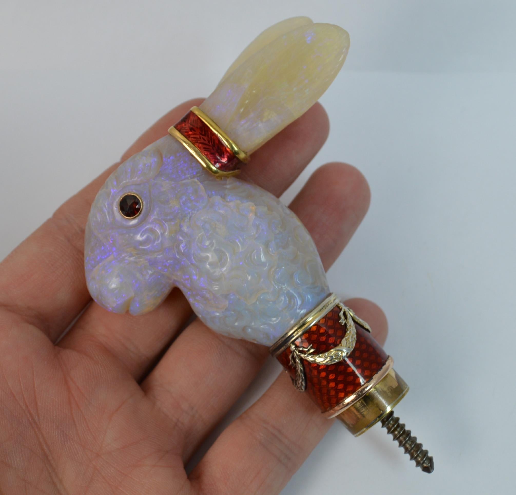
A striking Rabbit shaped walking cane or parasol handle top.

Designed as a rabbit and made from large pieces of hand carved natural opal. Set with a garnet to each eye and rich red enamelling to the ears and the base. 

Complete with original