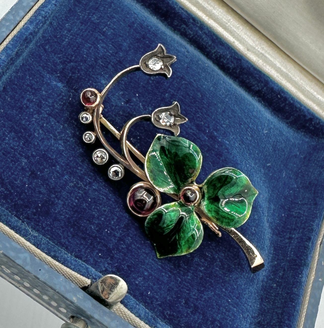 This is an exquisite and rare antique FABERGÉ Rose Cut Diamond, Enamel and Red Cabochon Brooch modeled as a sprig of flowers with a translucent green enameled flower centered with a red cabochon and the tendrils terminated in tulip form flowerheads
