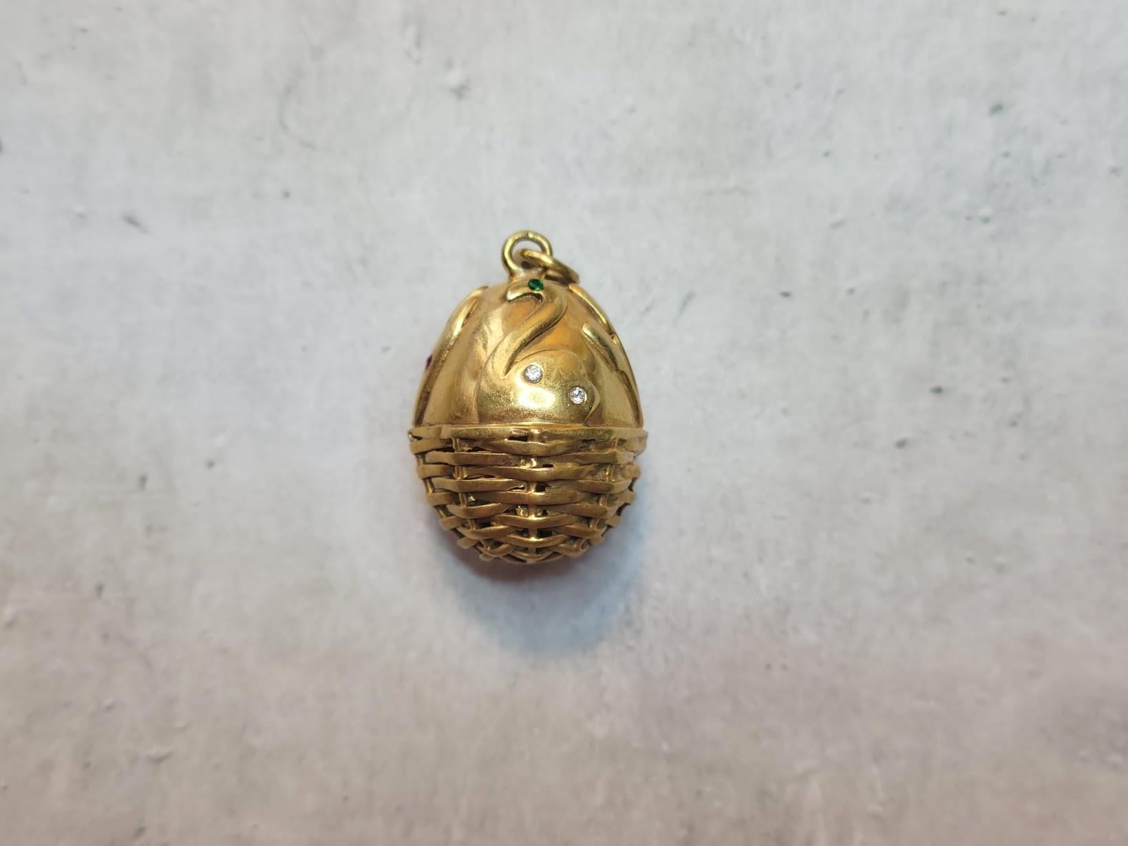We are pleased to present another unique piece from our collection – a gilt silver egg pendant elegantly designed with a basket motif at the base. The top features intricately crafted swans and reeds adorned with tiny diamonds, rubies, and emeralds.