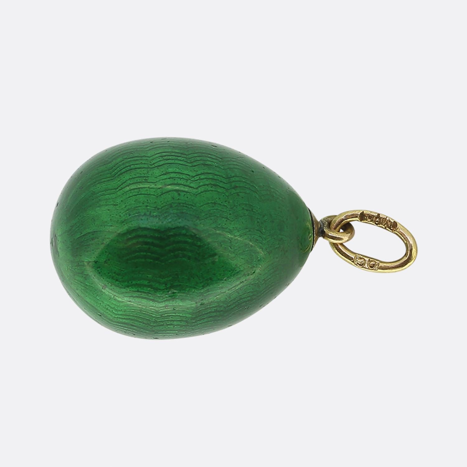 Here we have a striking Fabergé pendant. This exquisite piece showcases a rich green egg-shaped design, crafted with meticulous attention to detail. The surface features a subtle wave pattern, adding depth and texture to the vibrant enamel. A