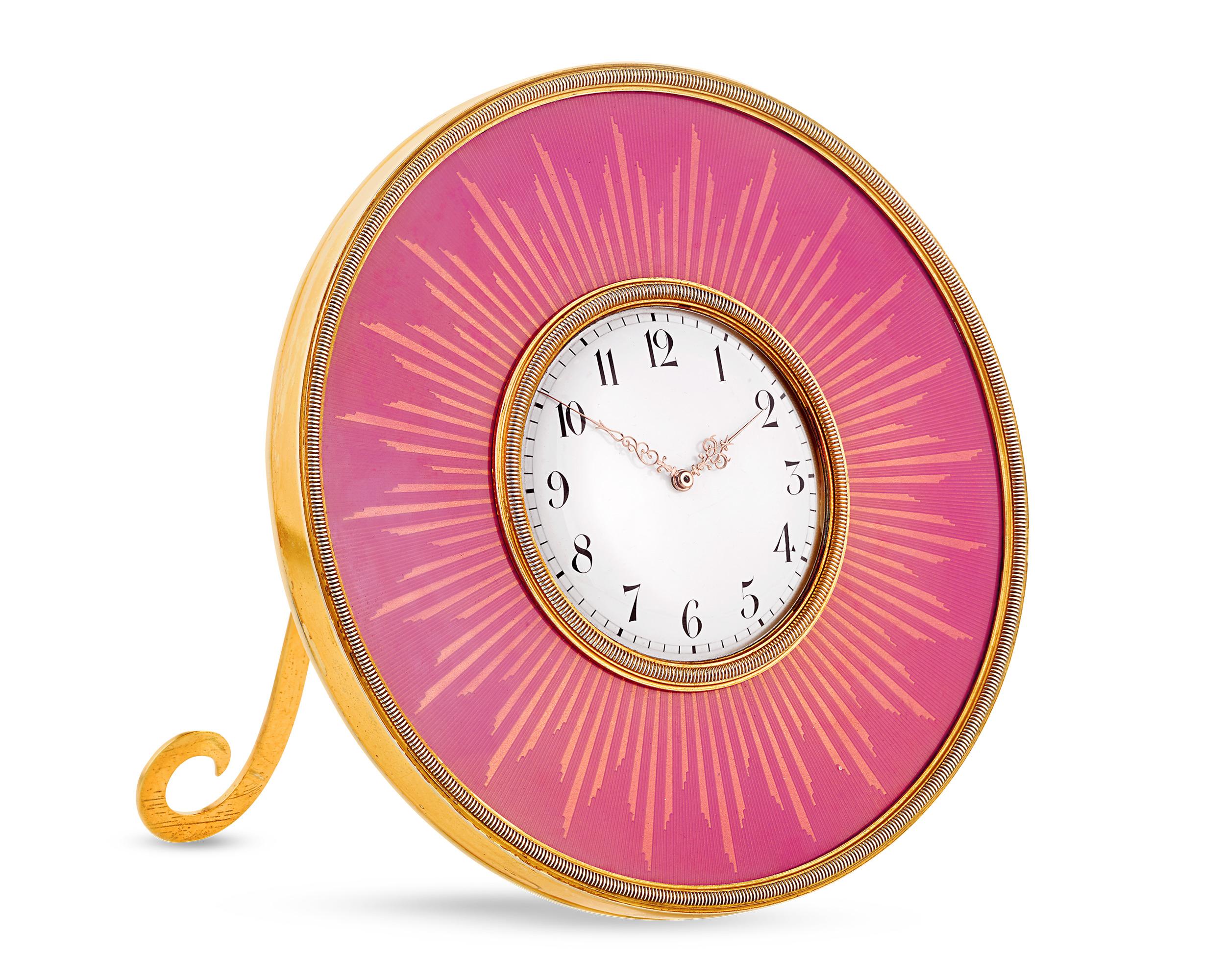 Plus qu'une simple horloge, ce garde-temps de la firme Revere Fabergé est une véritable œuvre d'art. Créée vers 1900 pendant l'âge d'or de Fabergé, cette exquise horloge de table circulaire est composée d'émail rose translucide rehaussé de dorures
