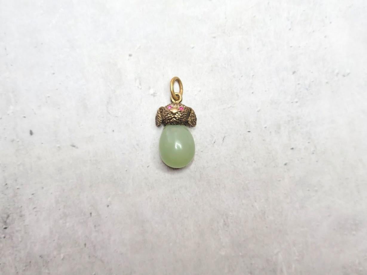 We present an adorable egg pendant in the form of a miniature carved gilt silver puppy's head with ruby eyes and a bowenite stone. The puppy's head is 88 imperial silver, and its eyes are encrusted with natural ruby gems. It is truly a cute piece of