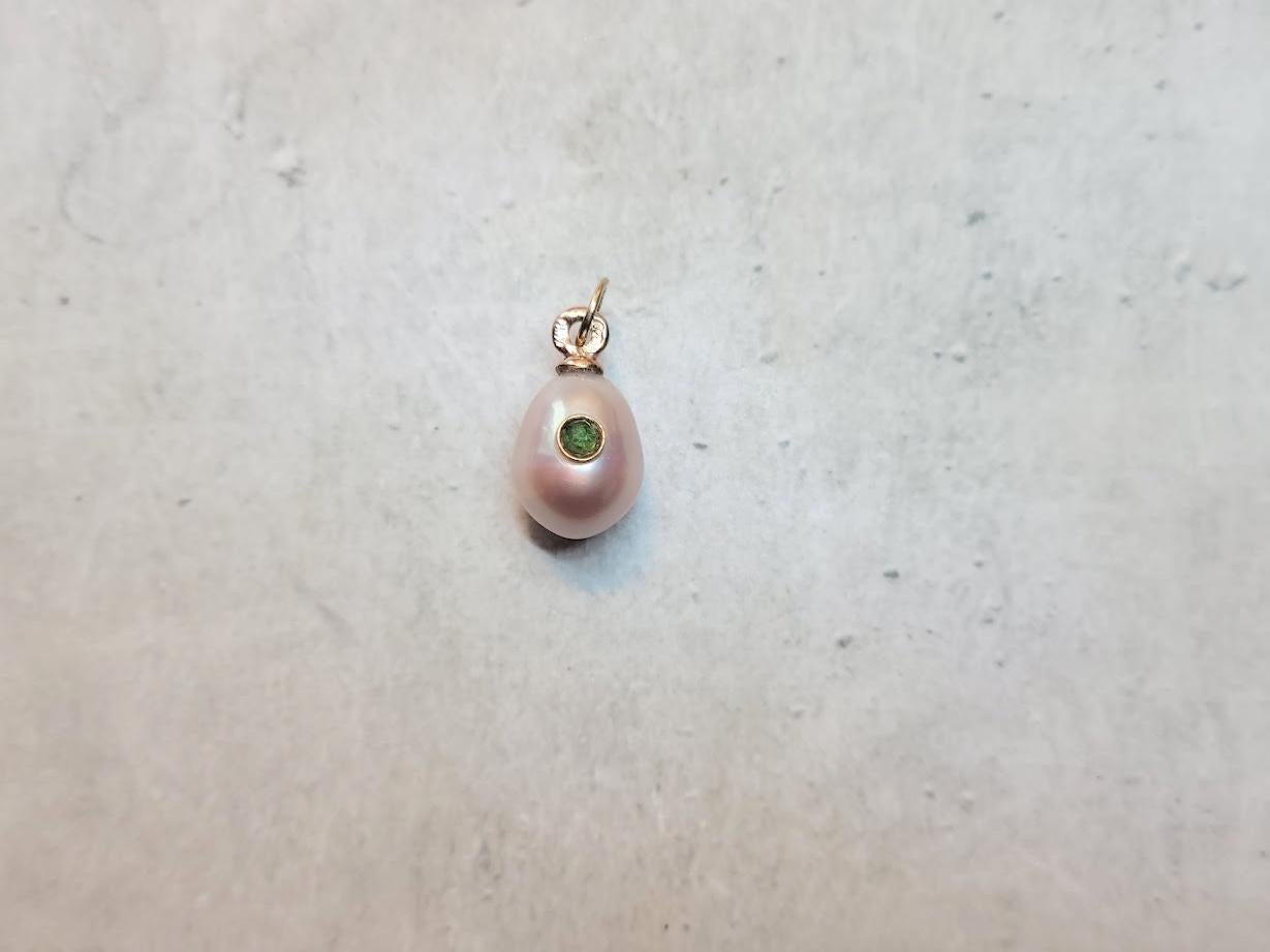We are pleased to present another exceptional item from our collection—a charming and highly unusual miniature rose gold egg pendant crafted from genuine pink pearl and adorned with one emerald element. This exquisite piece is attributed to one of