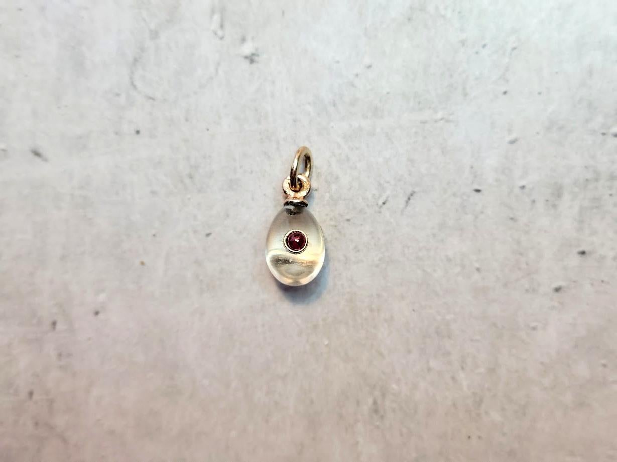 We are pleased to present another exceptional item from our collection—a charming and highly unusual miniature gold egg pendant, crafted from rock crystal and adorned with a ruby element. This exquisite piece is attributed to one of Fabergé’s most