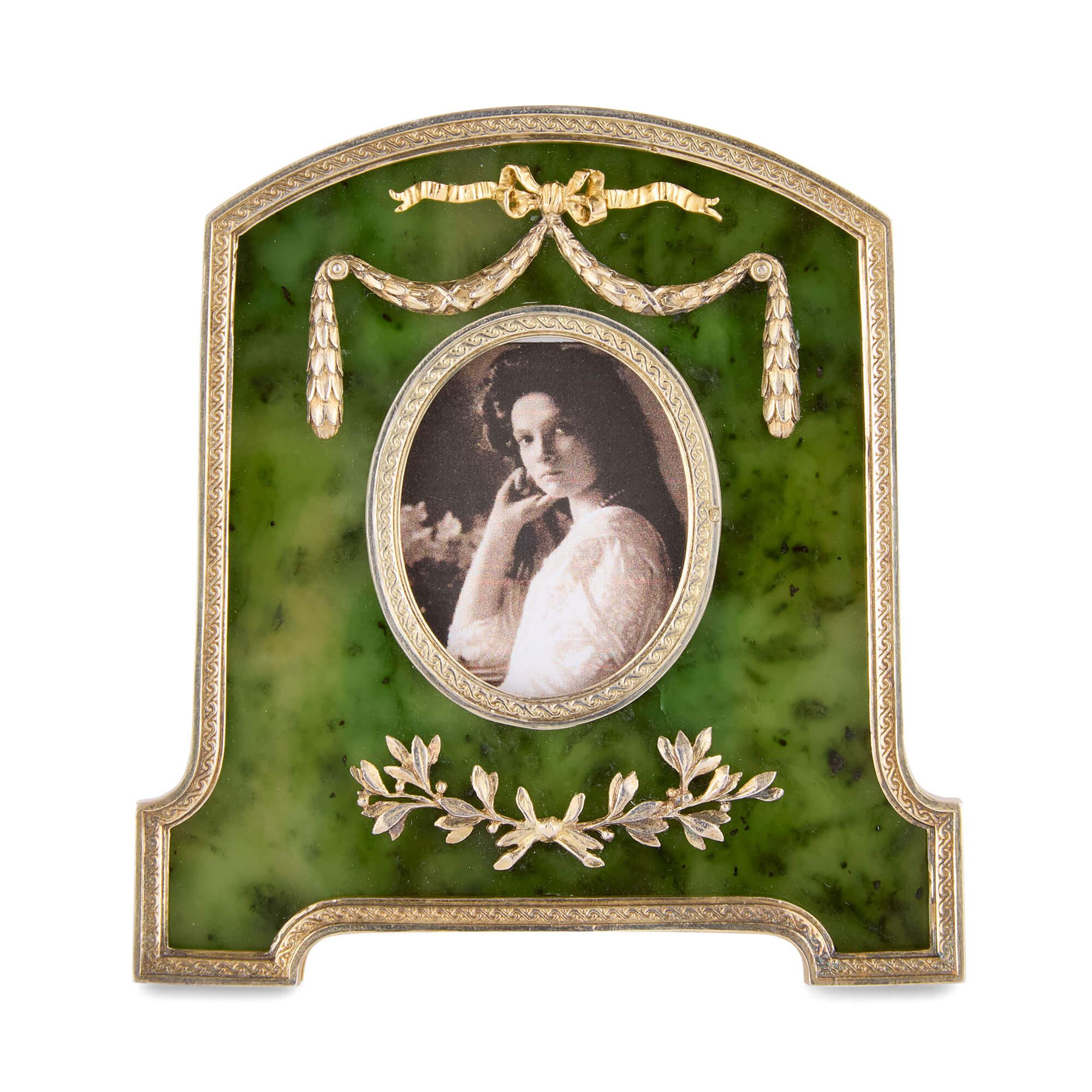 Marco de fotos de nefrita y vermeil inspirado en Fabergé
Continental, siglo XX
Marco: Alto 8,5 cm, ancho 8 cm, fondo 1 cm/ 5 cm (abierto)
Caja: Alto 5,5 cm, ancho 12,5 cm, fondo 12,5 cm

Este impresionante marco de fotos de nefrita está elaborado en
