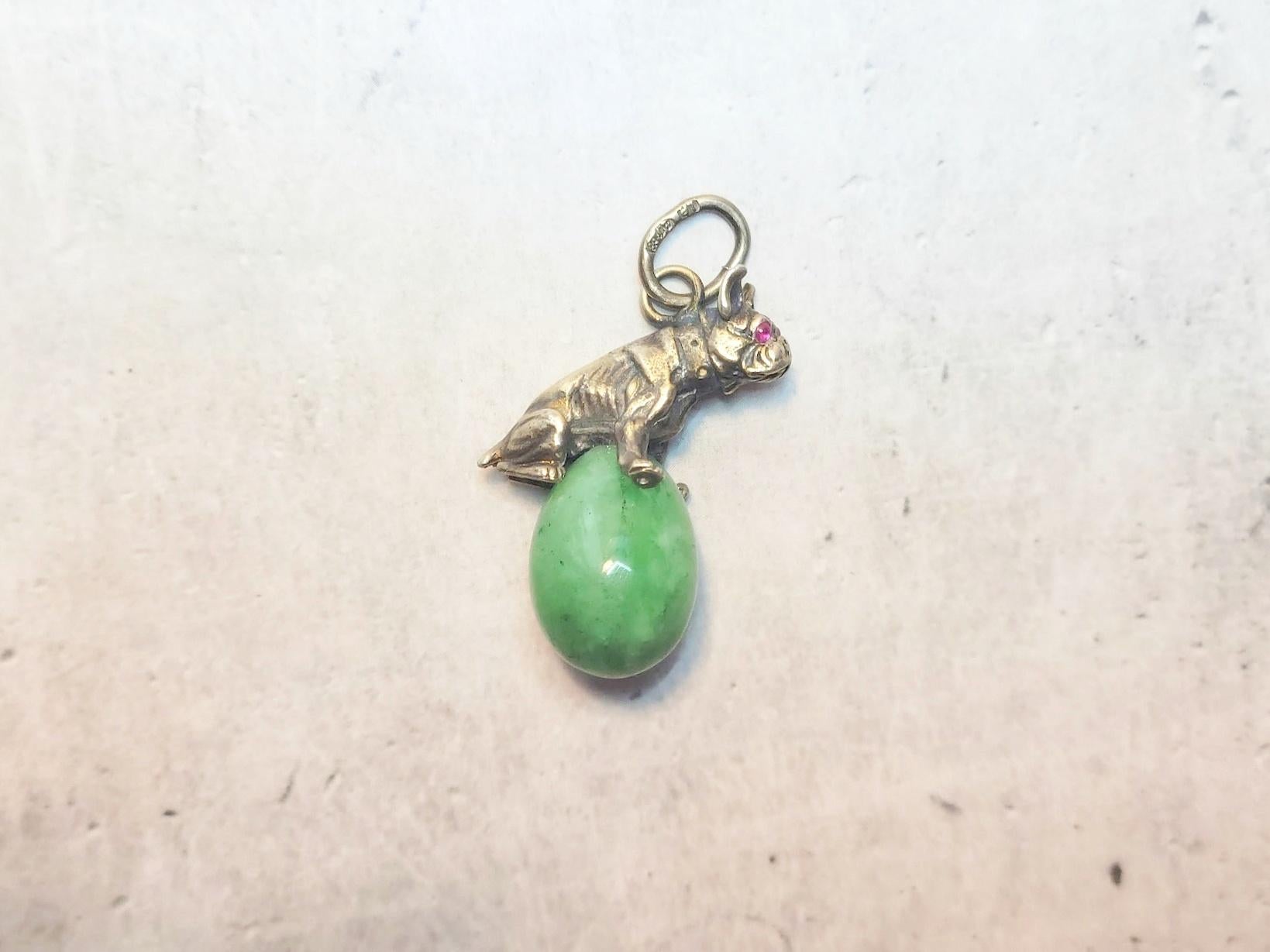We present to your attention a unique and extraordinary piece from our collection — a jade egg pendant featuring a silver bulldog figurine with ruby eyes, created by the legendary master Julius Rappoport. 
The pendant is made of natural Russian