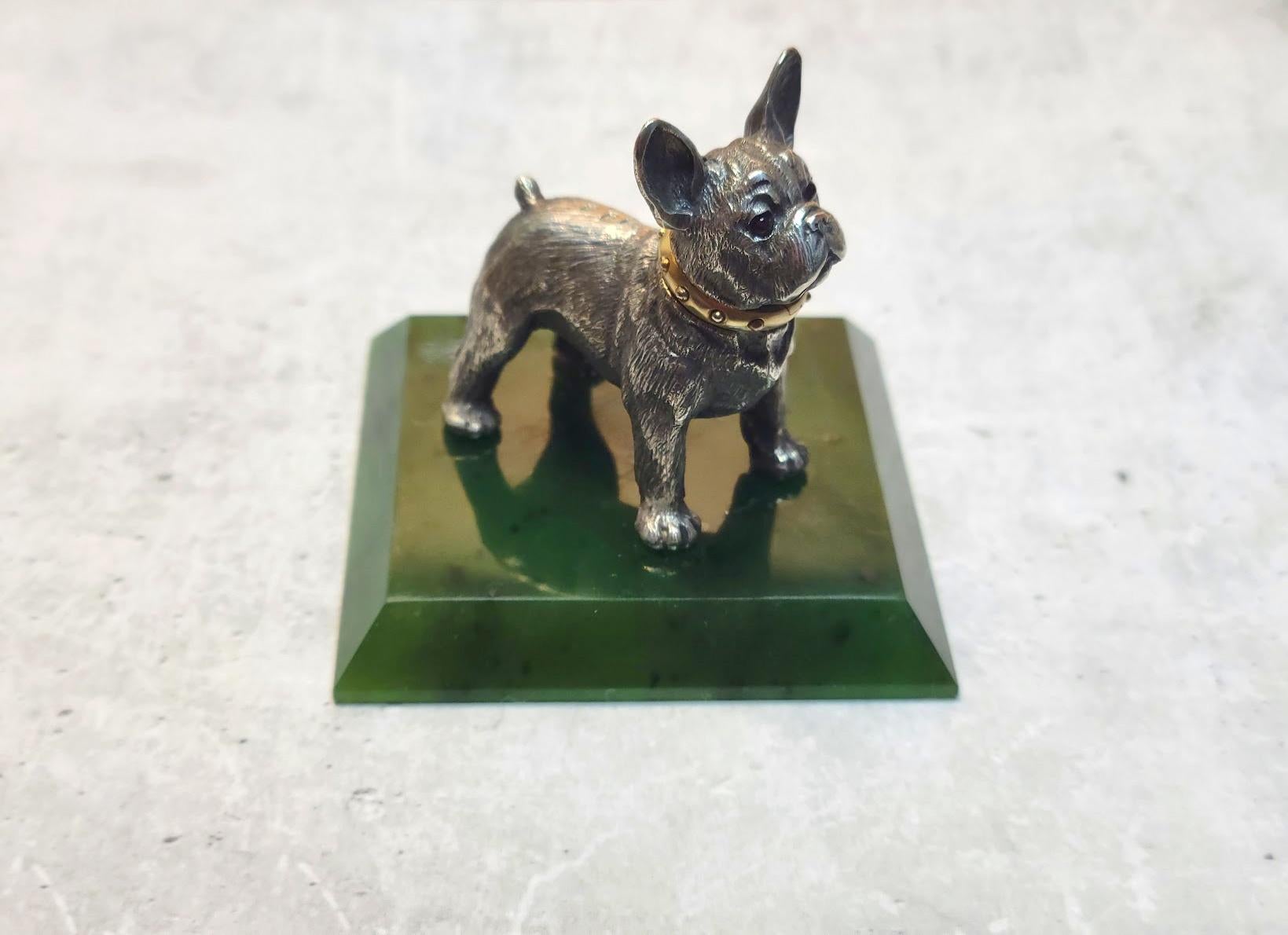 Allow us to present yet another treasure from our collection—an antique figurine from the era of the Russian Empire, crafted in the workshop of the illustrious Carl Fabergé. This exquisite miniature depicts a silver French bulldog with ruby eyes and
