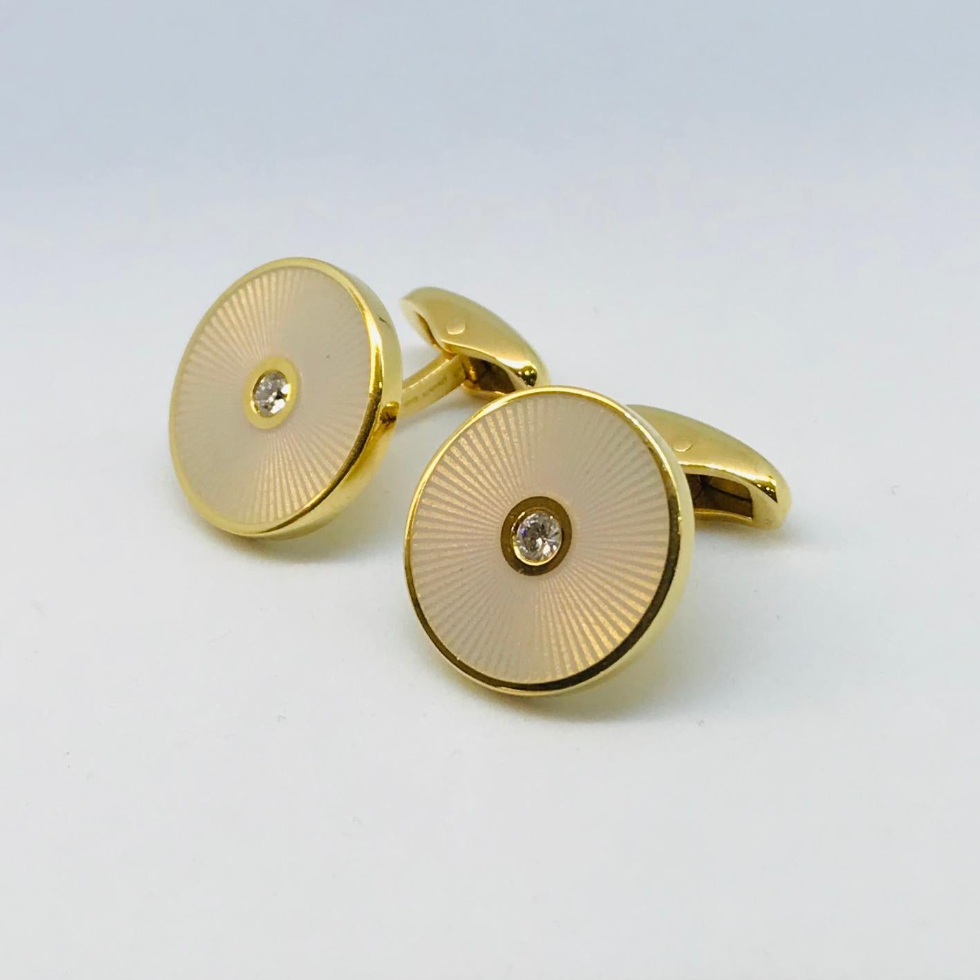 One pair of Fabergé limited edition 18K Yellow Gold Opalescent White French Guilloché enamel and diamond Round shaped cufflinks. Each cufflink centers one bezel-set round brilliant cut diamond surrounded by the translucent enameled “sun-ray” pattern
