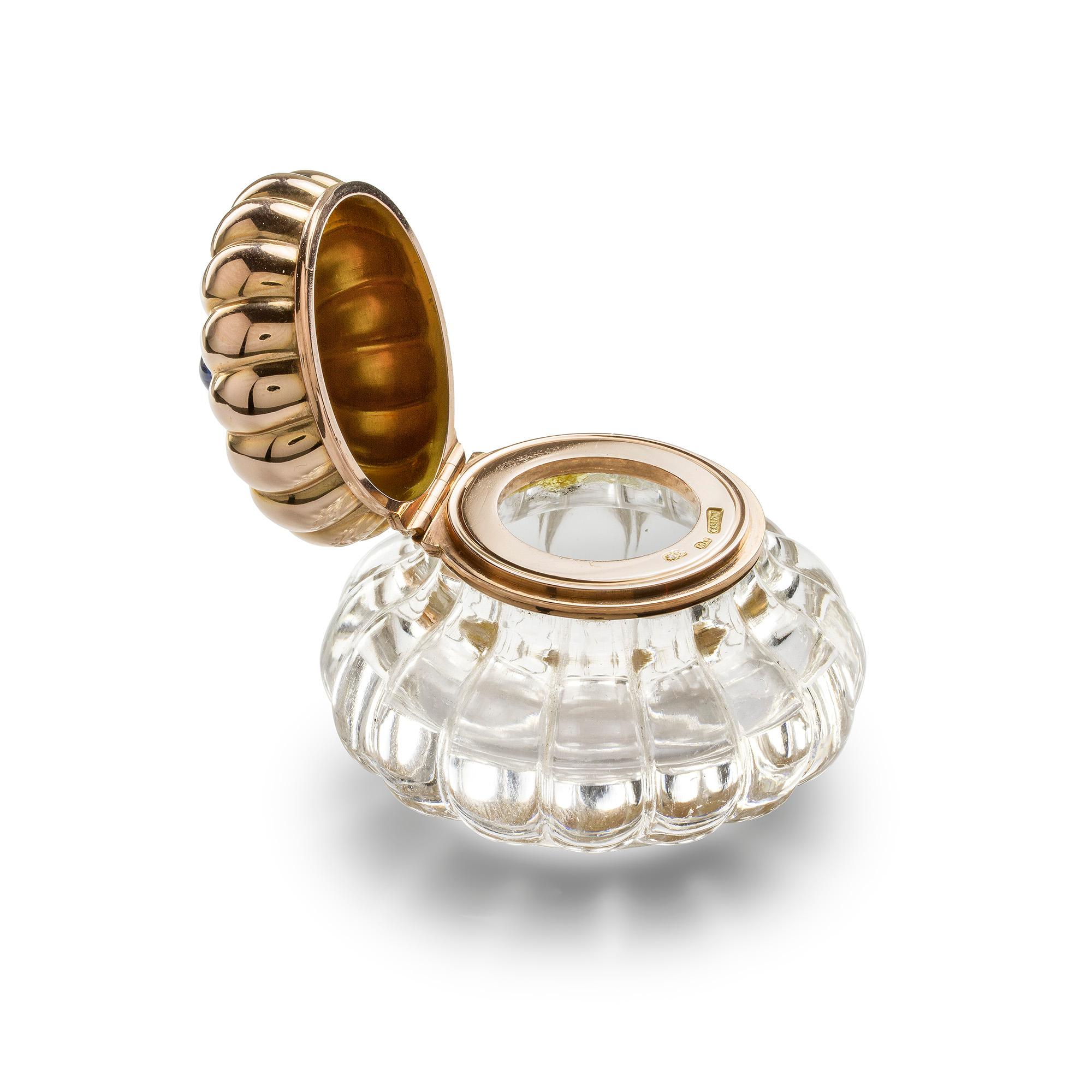 Encrier en or et cristal de roche Fabergé, le corps lobé en cristal de roche sculpté avec des côtés en forme de bombe, le couvercle à charnière en or également lobé et surmonté d'un saphir cabochon, marqué Fabergé avec les initiales du maître