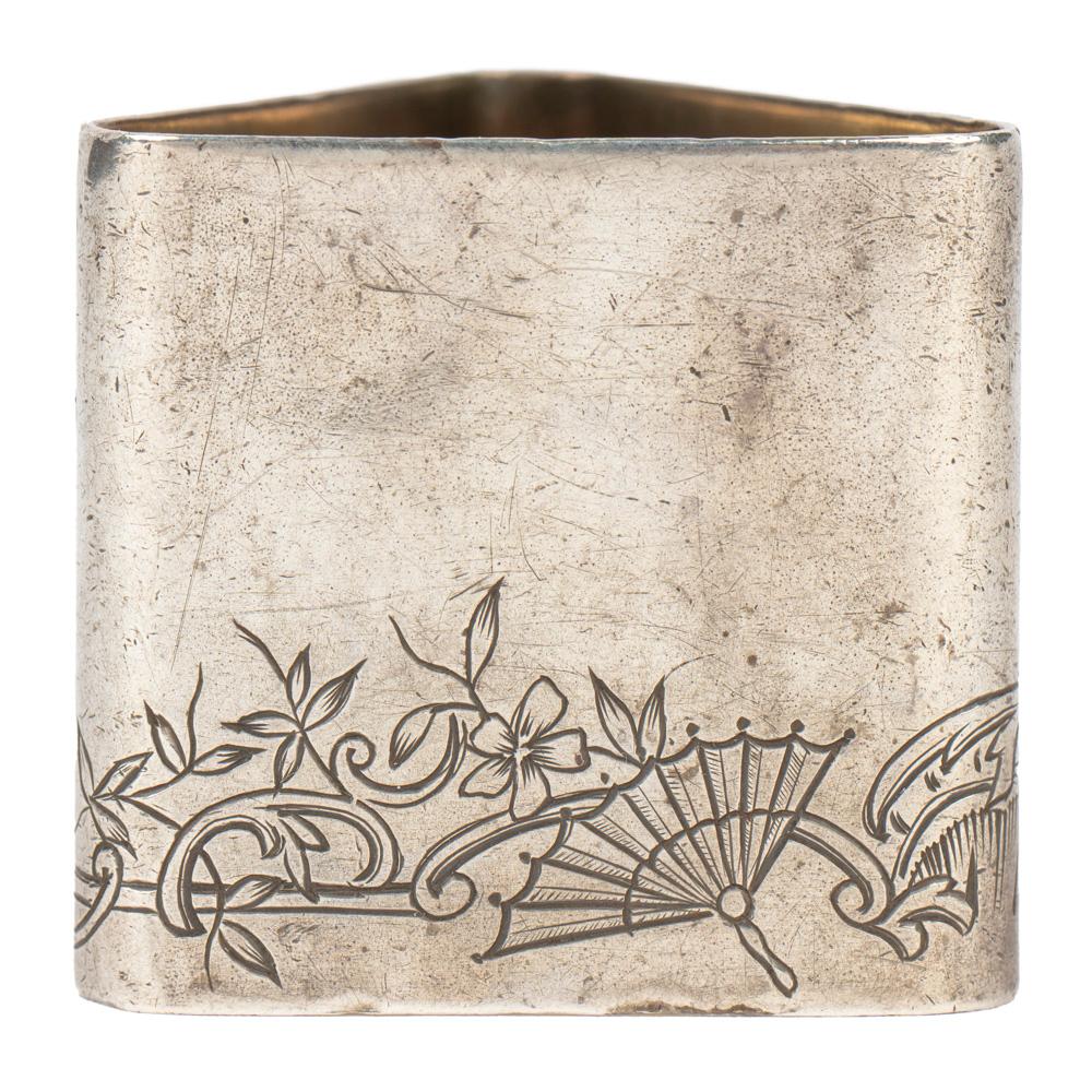 Triangular by Fabergé, from the era of Tsar Nicholas II, the base engraved with a band of scrolling foliage, flowers and a fan in the Japonisme style. Its triangular rather than round shape also reflects Japanese elements. 

Marked with Cyrillic
