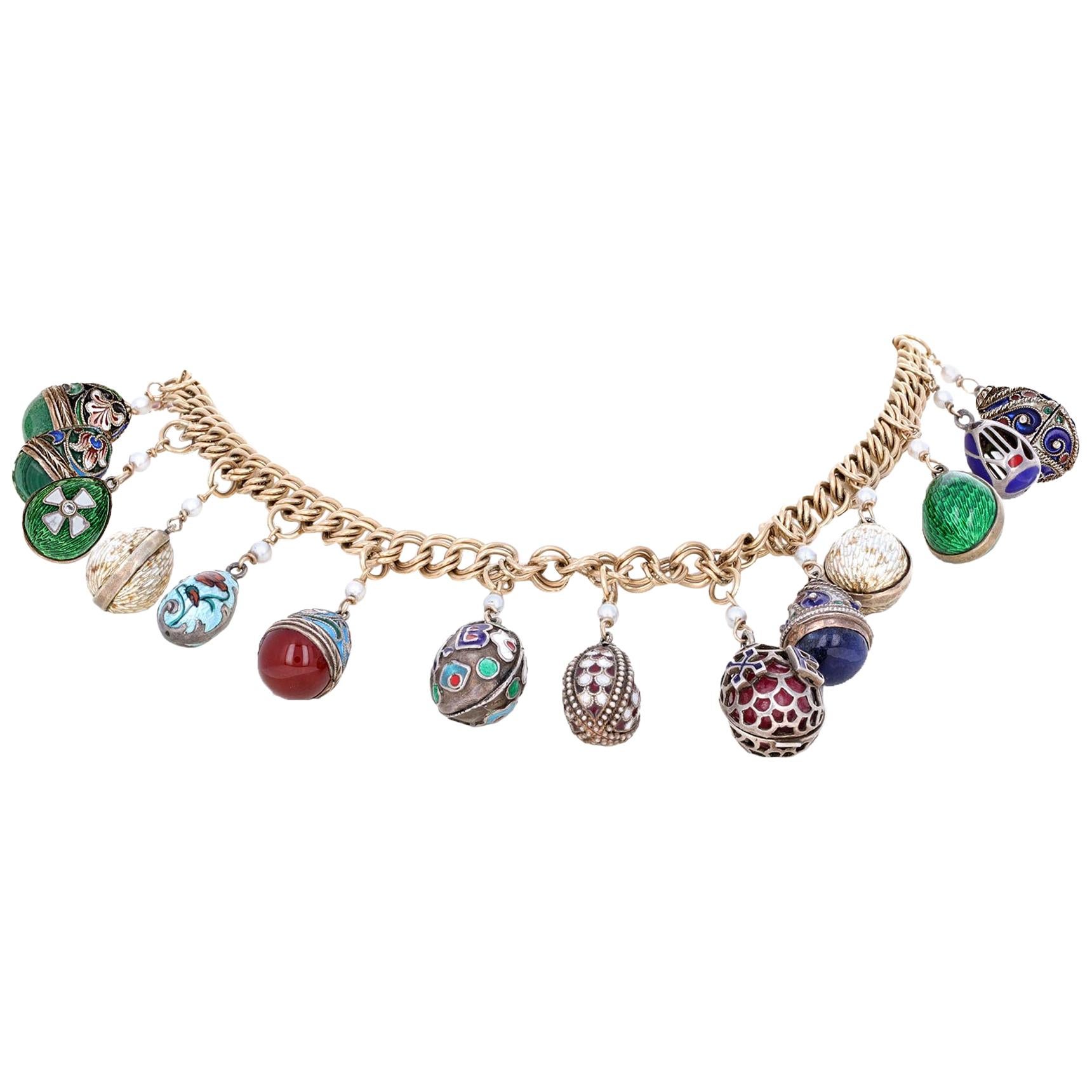 14 karat yellow gold enameled Faberge style charm necklace. This modern take on the classic Faberge features hanging eggs in blues, greens, reds and white enamel. The eggs are hanging from an 14 karat yellow gold chain. The eggs are hand made with