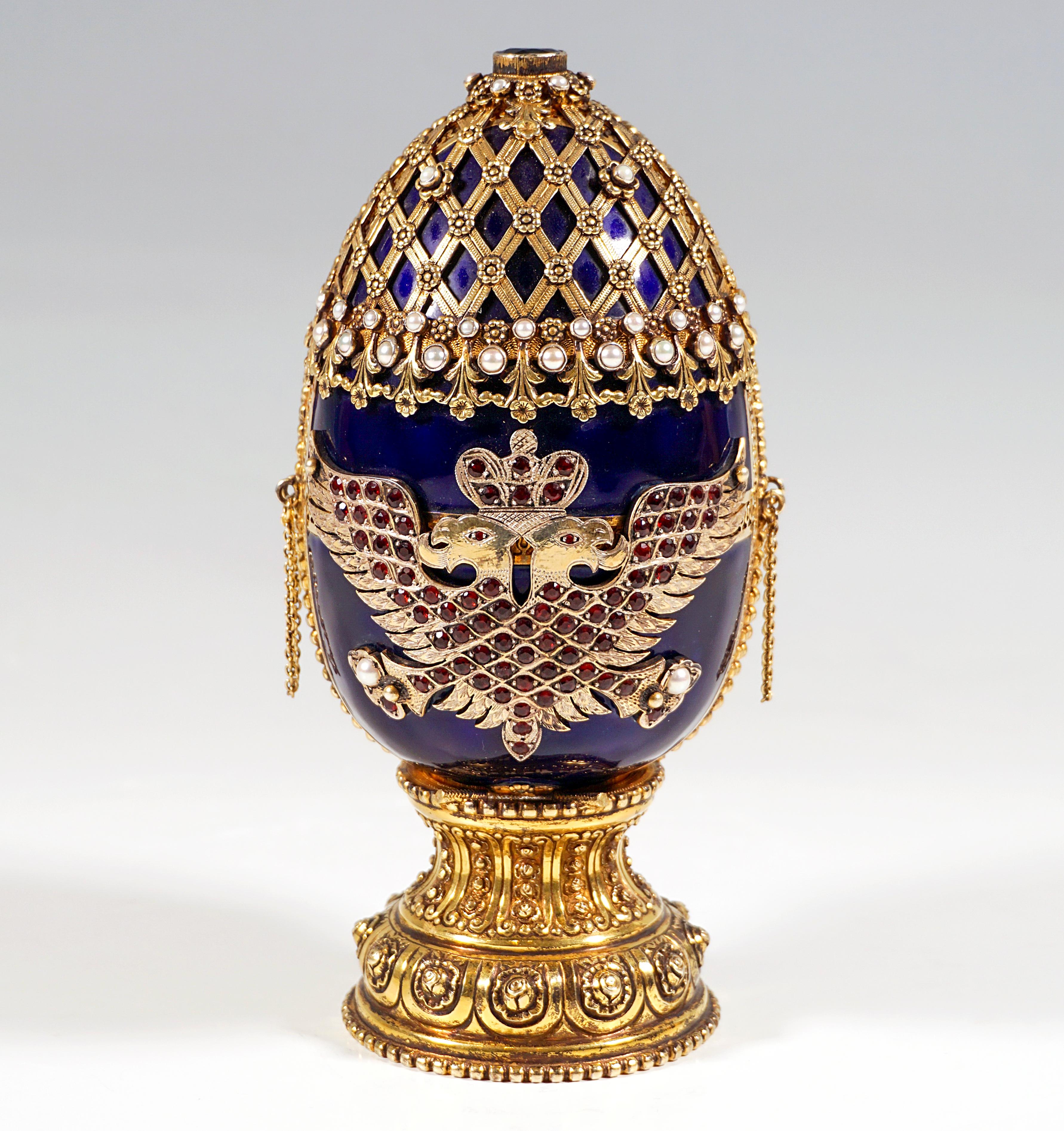 Cobalt blue enamelled decorative egg on a constricted round base with rosette ornaments, the front and back wall each covered with a double-headed silver eagle with set polished garnets on one side, with pearls on the other side, above, on the upper