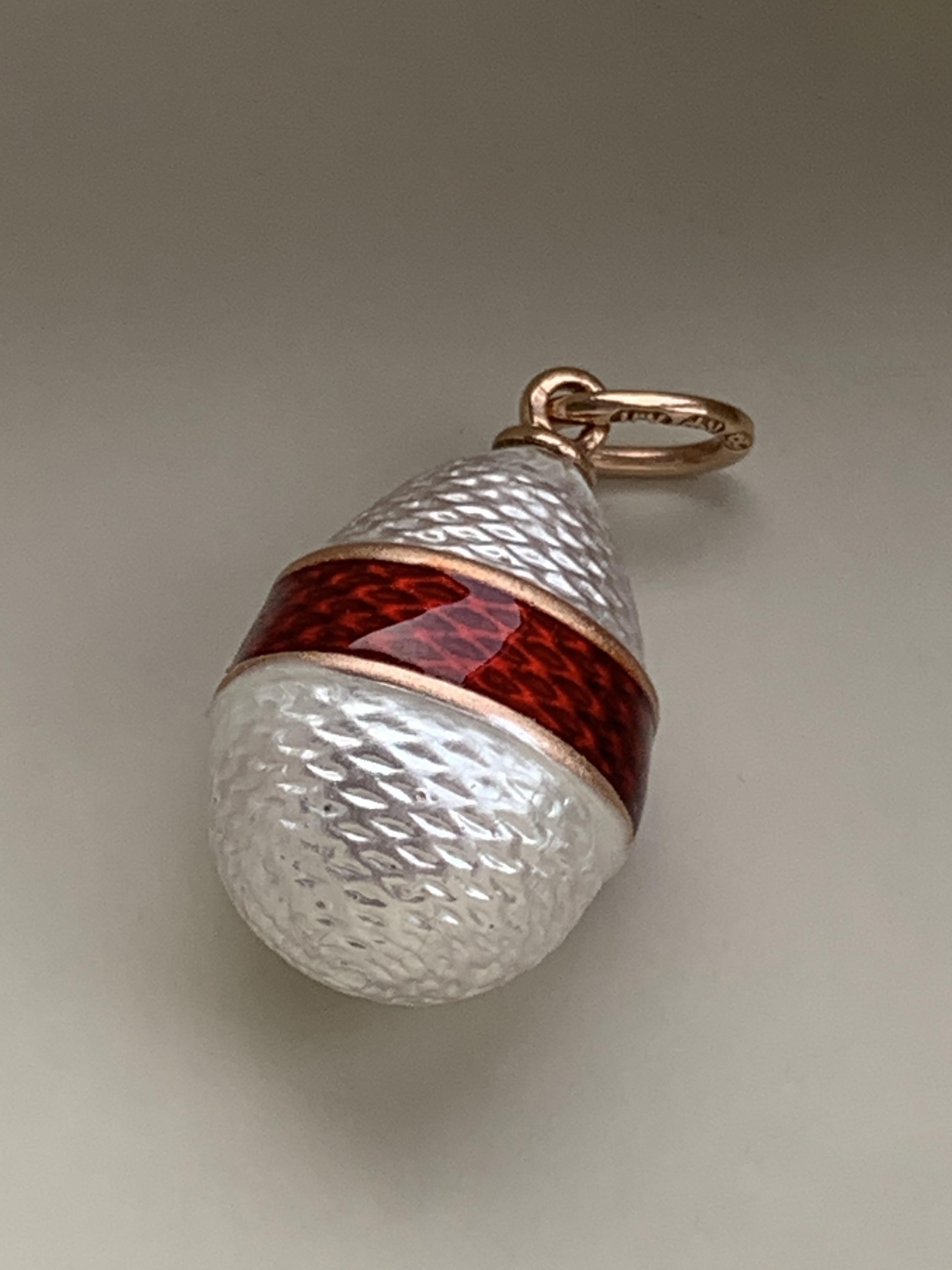 This exquisite pearl white guilloche- strawberry red banded egg pendant
was produced by the House of Faberge between 1829 - 1903
the rose gold Jump ring has clear markings of AH for
the workmaster August Holmstrom and
also marked 56 - for 14ct Gold