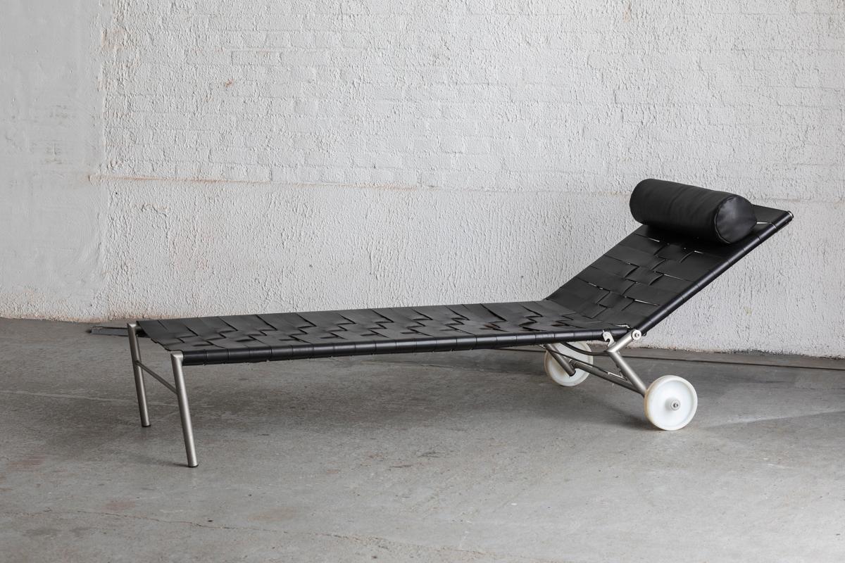 Rare lounge chair/daybed, designed by Fabiaan Van Severen and produced in Belgium in 1996. This rare daybed is made from thick black saddle leather woven over a tubular metal frame. The acrylic heavy duty industrial wheels make it easy to move