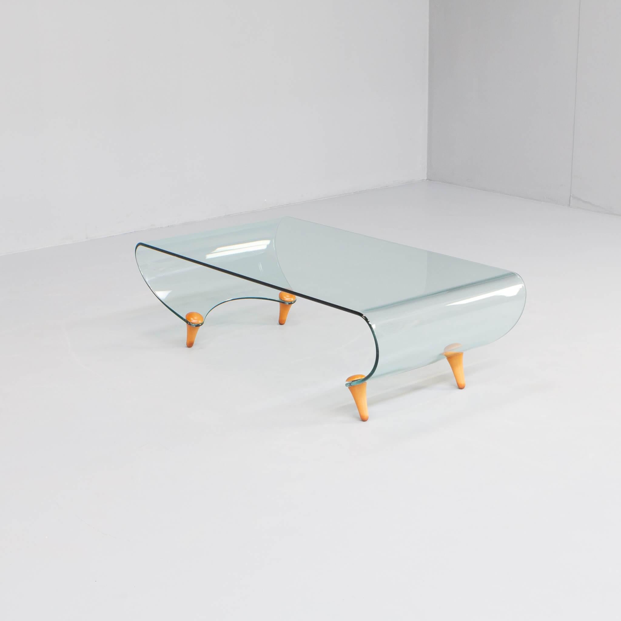 This coffee table was designed in 1996 by Fabio di Bartolomei for Fiam Italy. The table has a curved glass and four wooden legs plan.No longer in production. Signed in the glass: FIAM Italian AB-II. Very good condition.This table is part of the