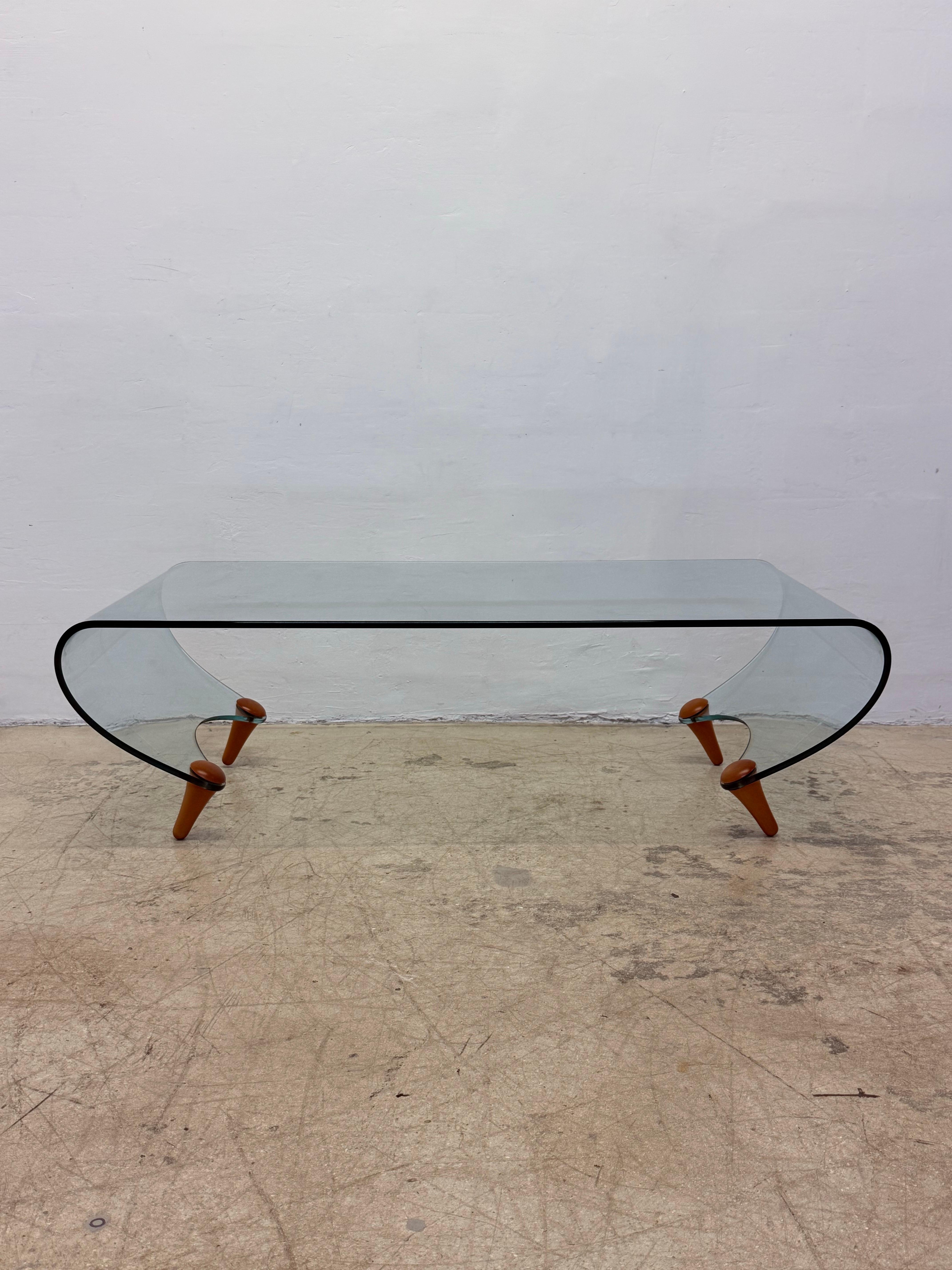 Rare curved glass Tango coffee table on four wooden peg legs designed in 1996 by Fabio Di Bartolomei for Fiam Italia.  Signed.