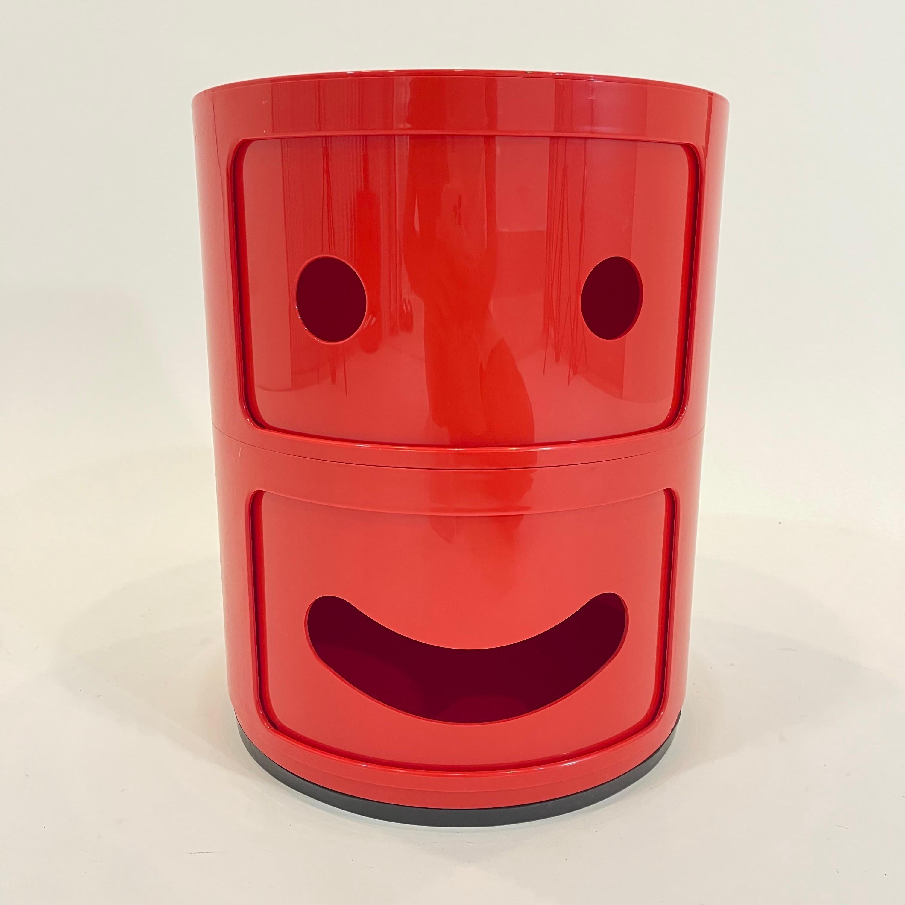 Iconic whimsical 2 door Red Componibili Smile cabinet a tribute to Anna Castelli Ferrieri's original design.  Rendered in batch dyed ABS plastic composed of a 2-tier Componibili cabinet with two eye holes cut in the upper cabinet door and one