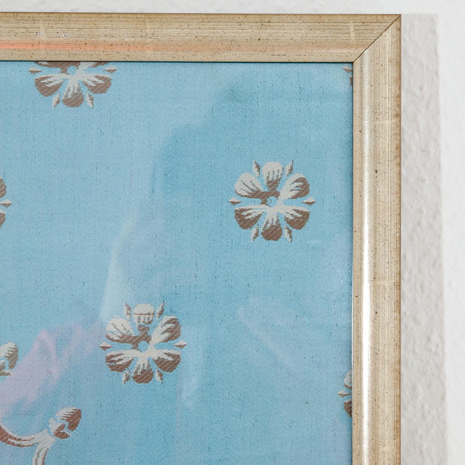 French fabric sample of circa 1810, framed behind glass. Silver vase and flower décor on a light blue field.