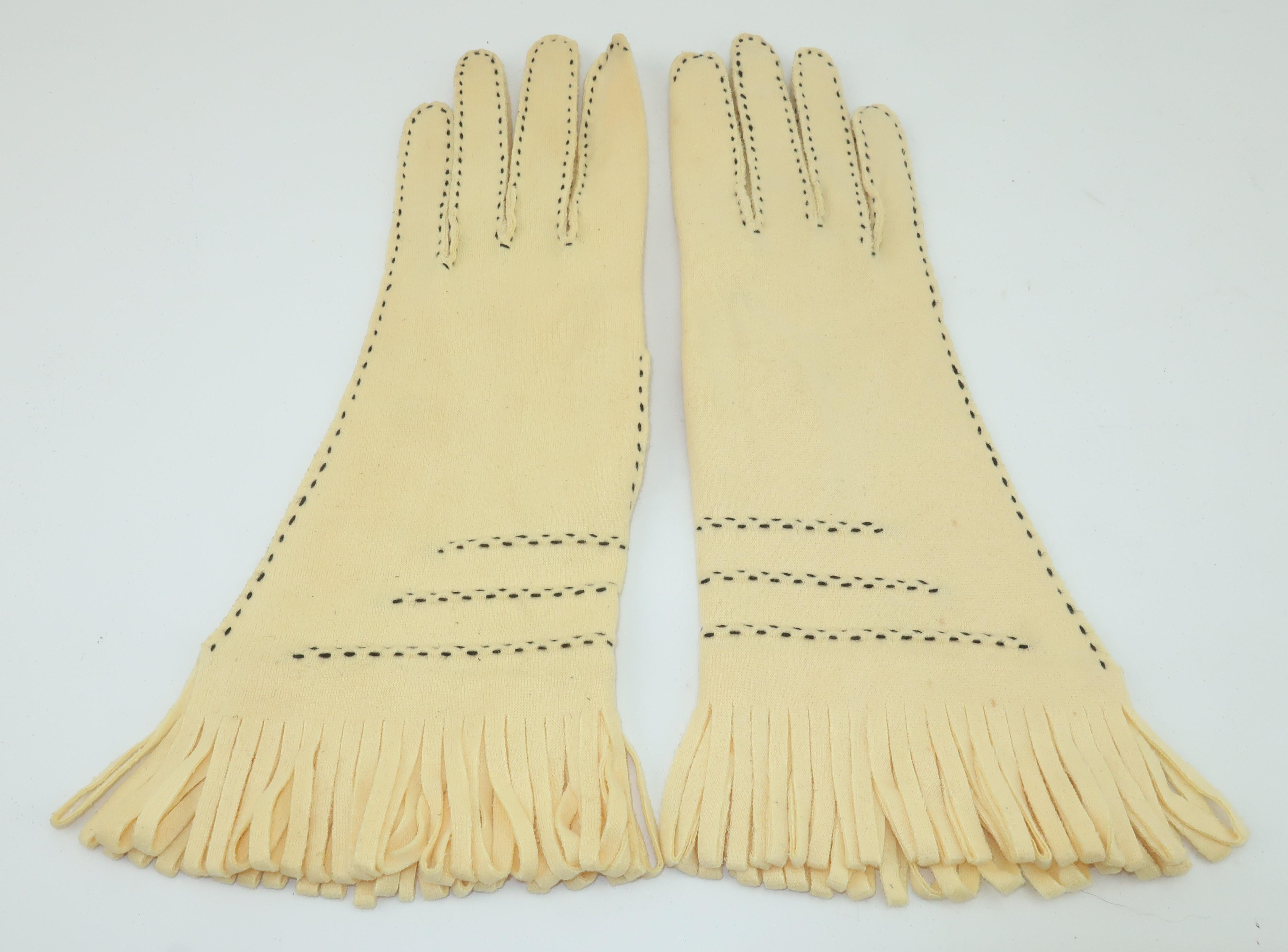 A pair of buttery yellow or creme fabric 1960's gauntlet gloves with black contrast stitching and looped fringe at the cuffs.  The look is reminiscent of fringed Western chamois riding gloves but definitely with a fashionable twist.  No