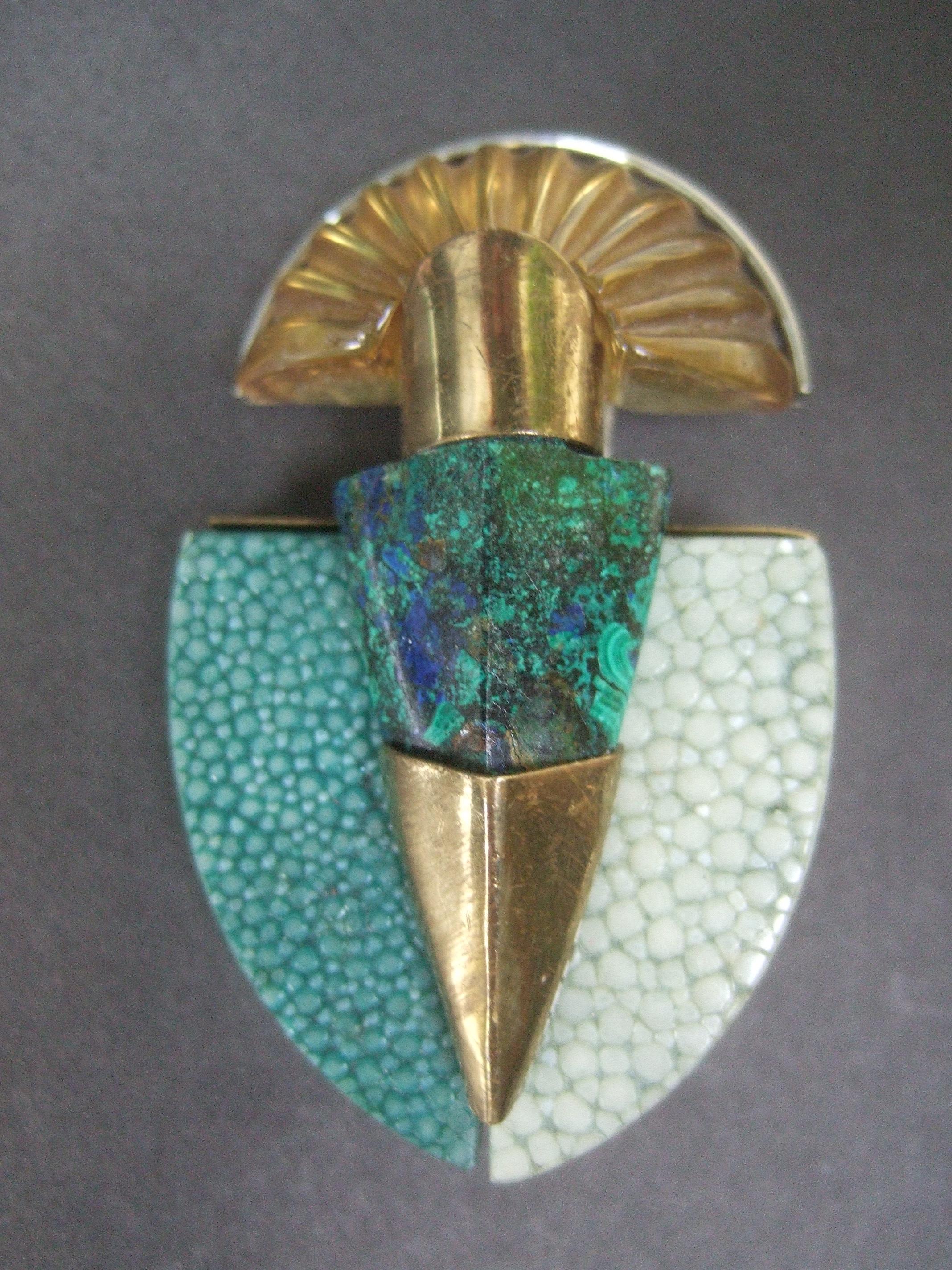 Fabrice Paris Avant-garde malachite stone & resin lucite gilt metal brooch c 1970

The elegant French brooch is designed with a geometric cut malachite stone in the center anchored with brass tone metal hardware. The upper section has a translucent