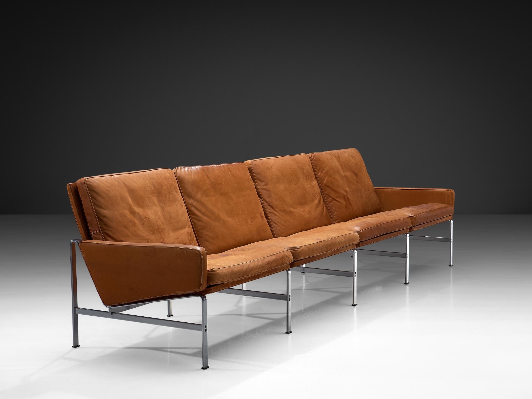Jørgen Kastholm & Preben Fabricius per Kill International, divano a quattro posti, pelle patinata, acciaio, Danimarca, 1960.

Il divano presenta una struttura solida, caratterizzata da linee chiare e decise e da forme geometriche vivaci. Il modo in