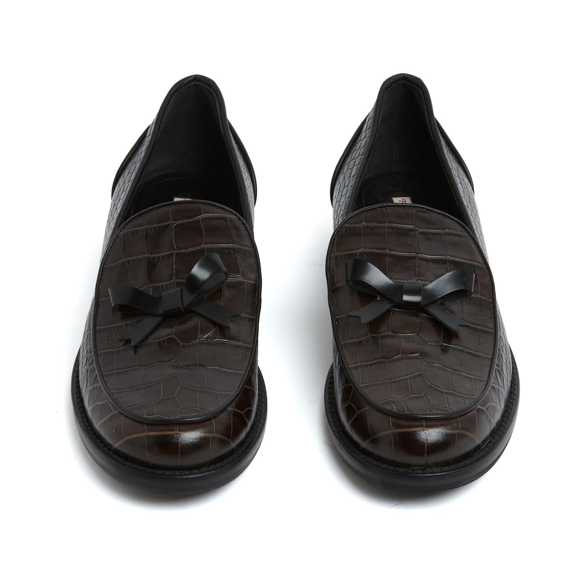 Mocassini Fabrizio Viti in pelle goffrata marrone molto scuro, quasi nera, bordati con profili neri e decorati con un fiocco nero, fodera in pelle e suola interna ed esterna. Taglia 38.5EU o UK5.5 e US8. I mocassini non sono mai stati indossati,